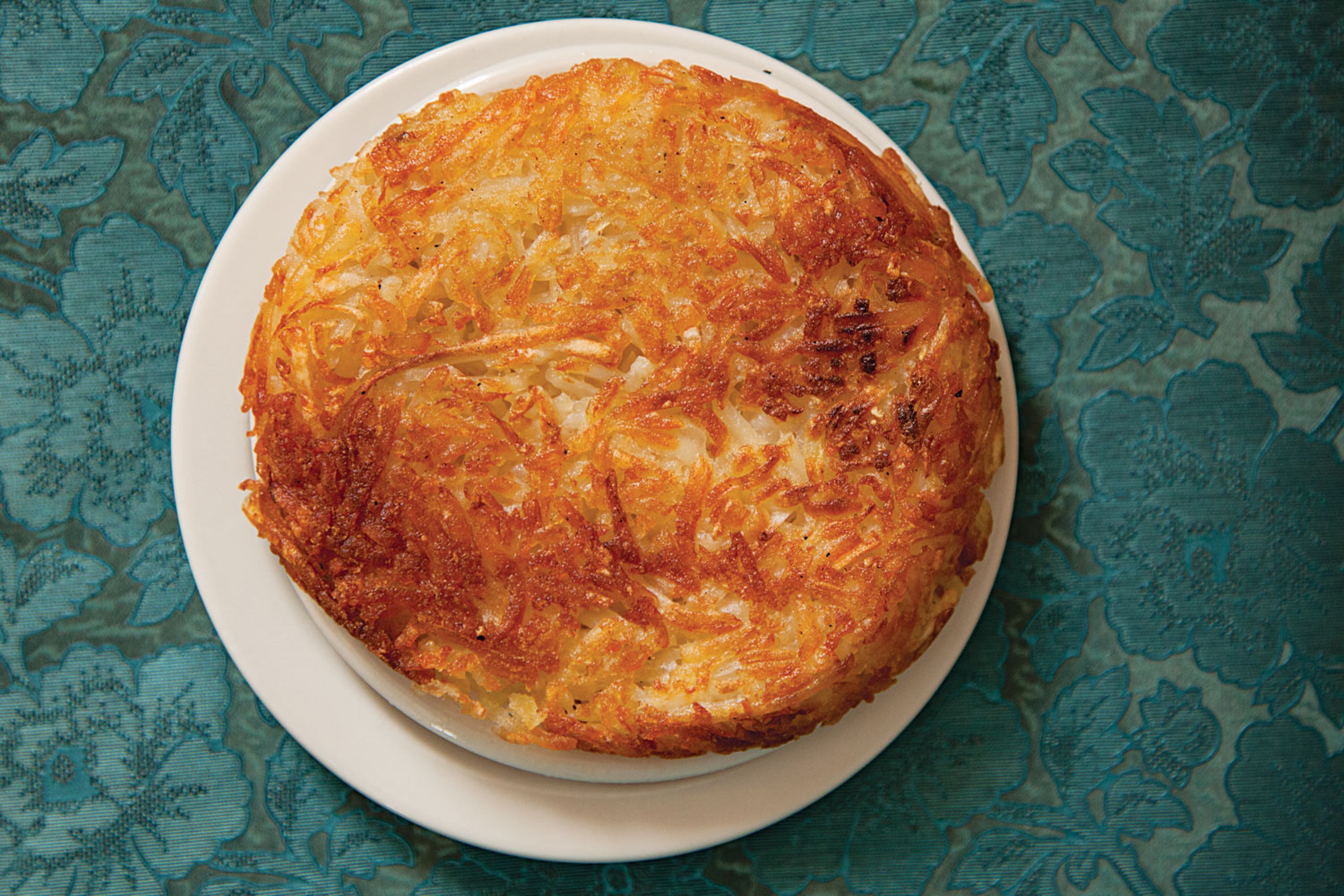 Fluffy inside and golden outside, these pan-fried potatoes are a signature of the Omaha restaurant Piccolo Pete's. Get the recipe for <a href="https://www.saveur.com/article/Recipes/Hashbrowns/">Hashbrowns</a>