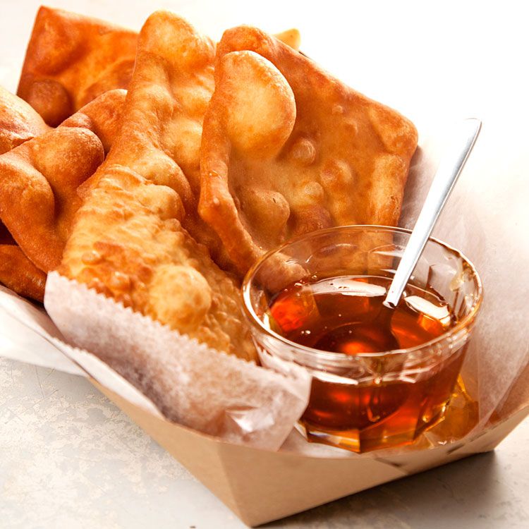 "I remember childhood visits to a restaurant on Albuquerque's Old Town Plaza. We'd press our noses to the glass as cooks rolled out the dough, cut it into squares or triangles, and plopped them into the vat of hot, bubbling fat, then, that dramatic moment, when the pallid little dough shapes magically inflated and turned golden brown. We'd seize one of the warm puffs of dough, bite off a corner, and drizzle honey into the hollow cavity." —<em>Cheryl J. Foote</em> Get the recipe for <a href="https://www.saveur.com/article/Recipes/Sopaipillas/">New Mexican Sopaipillas</a>
