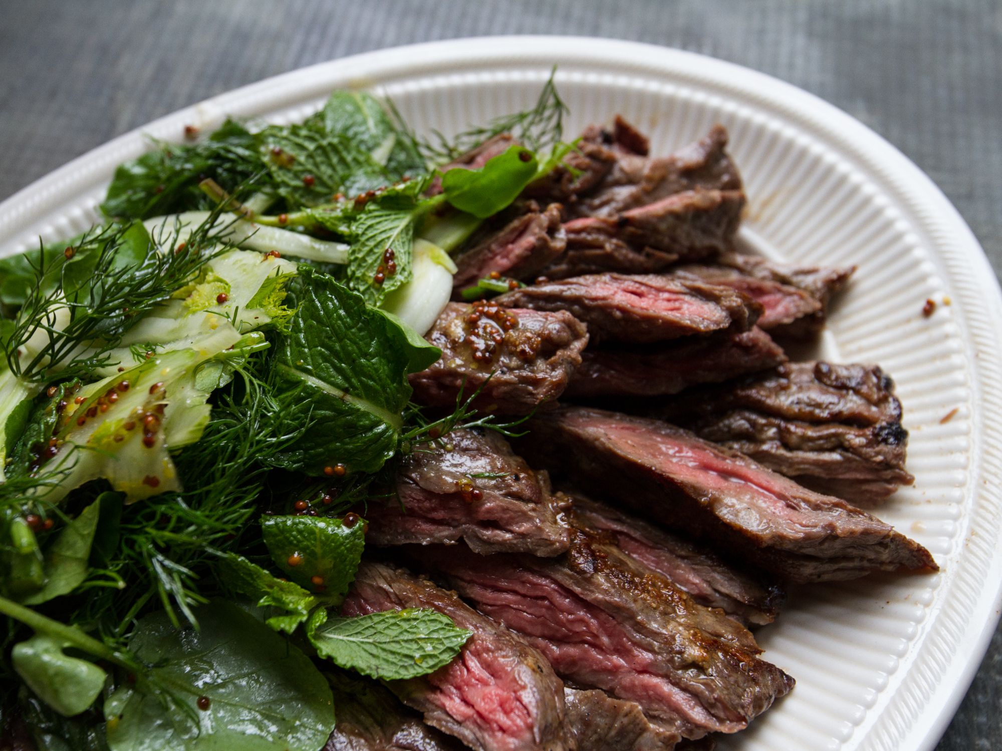 This steak is seasoned simply with salt and pepper and served with a light herb salad with a whole grain mustard and honey dressing. Get the recipe for <a href="https://www.saveur.com/article/recipes/grilled-skirt-steak-with-herb-salad/">Grilled Skirt Steak with Herb Salad</a>