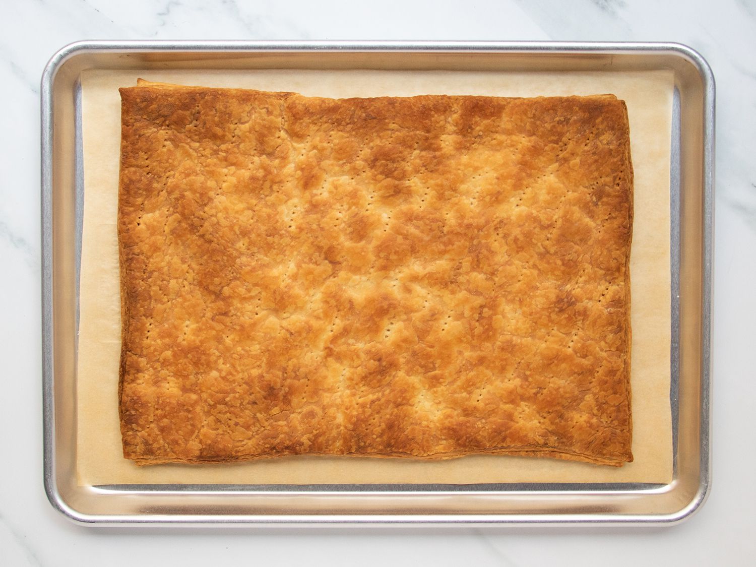 Fully baked puff pastry sheet set in rimmed baking sheet