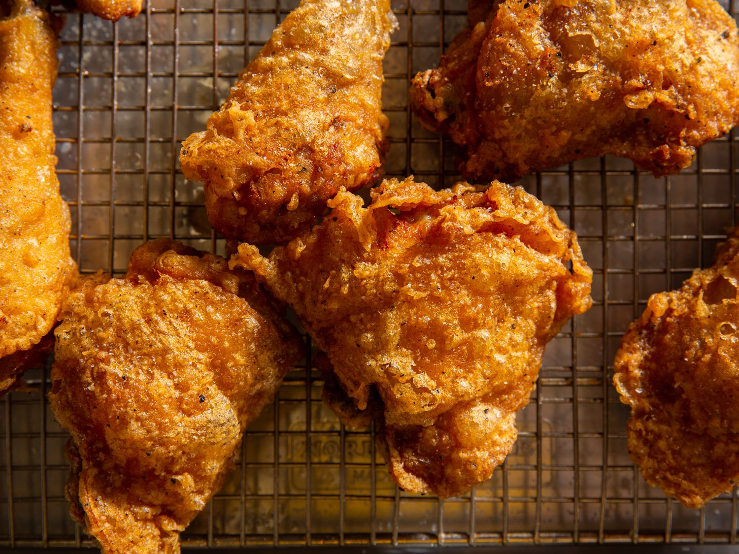 Batter-fried chicken pieces resting on a wire rack set in a rimmed baking sheet