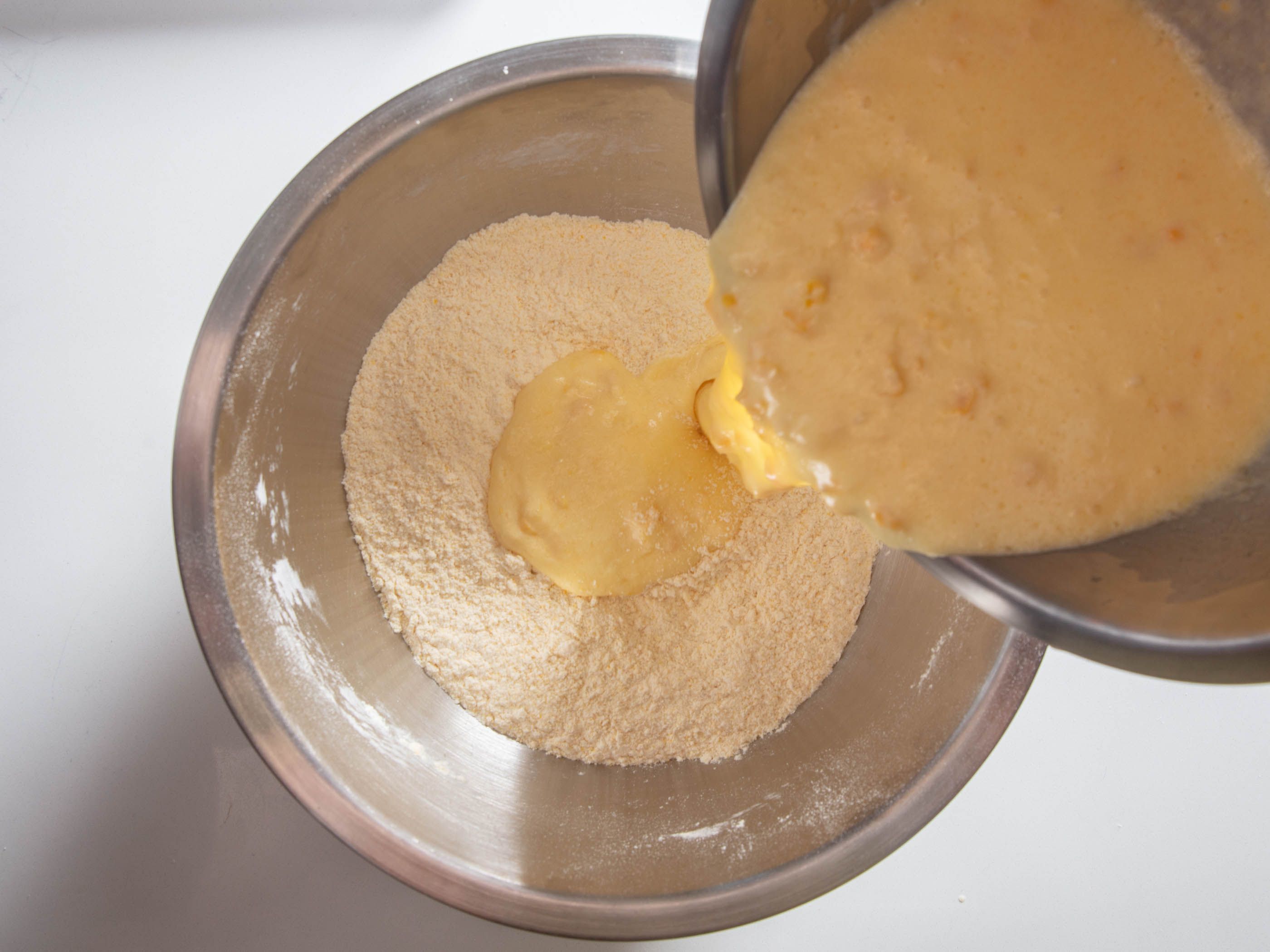 Wet ingredients being mixed with dry ingredients for cornbread muffins