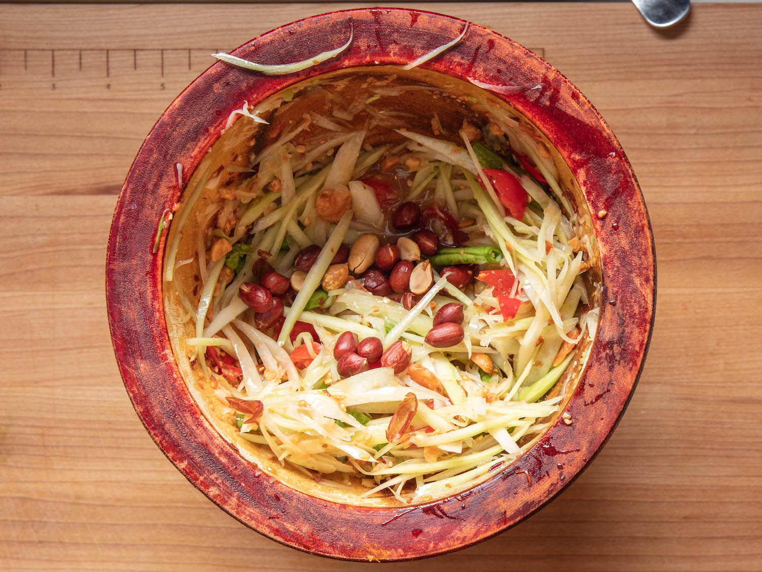 Dressed som tam salad in wooden mortar.