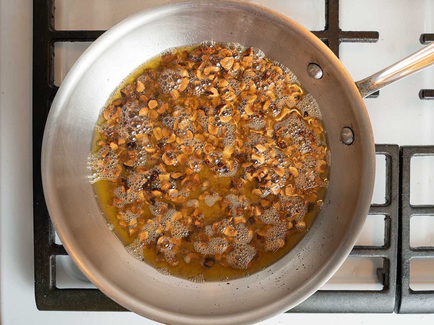 Hazelnuts toasting in olive oil with cayenne in a saute pan