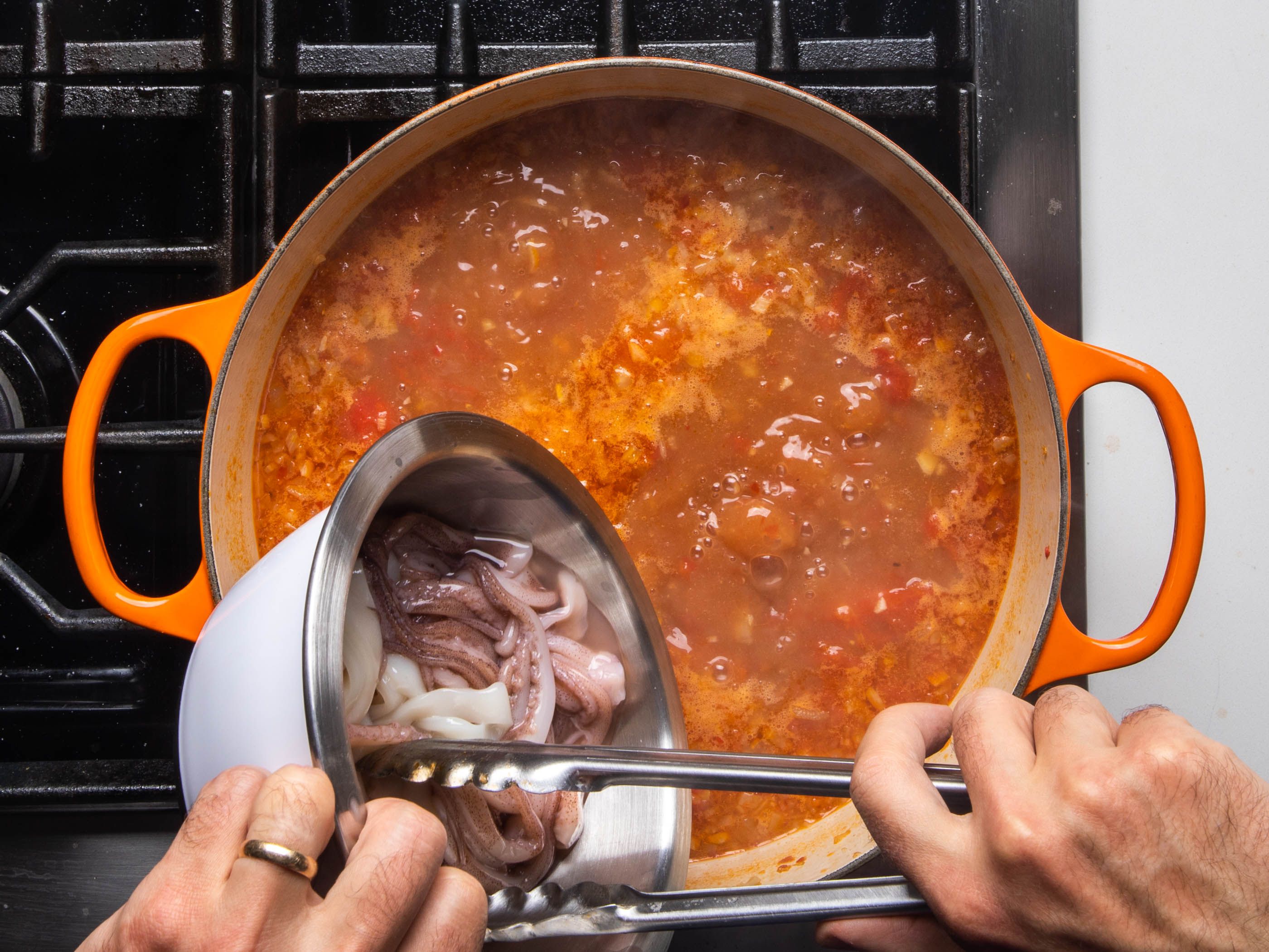 Squid being added to the cioppino.