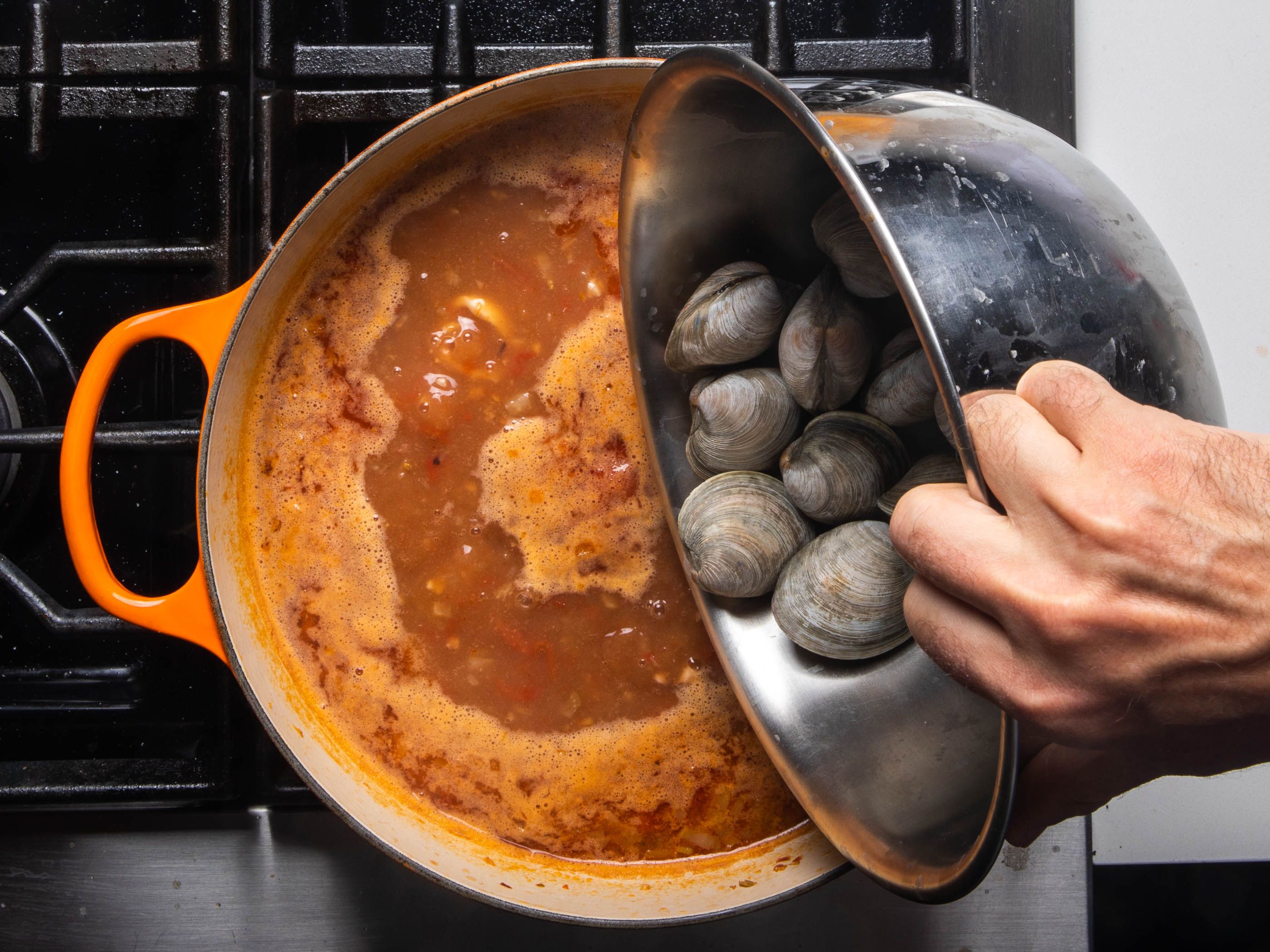 Adding the clams to the cioppino broth to cook.