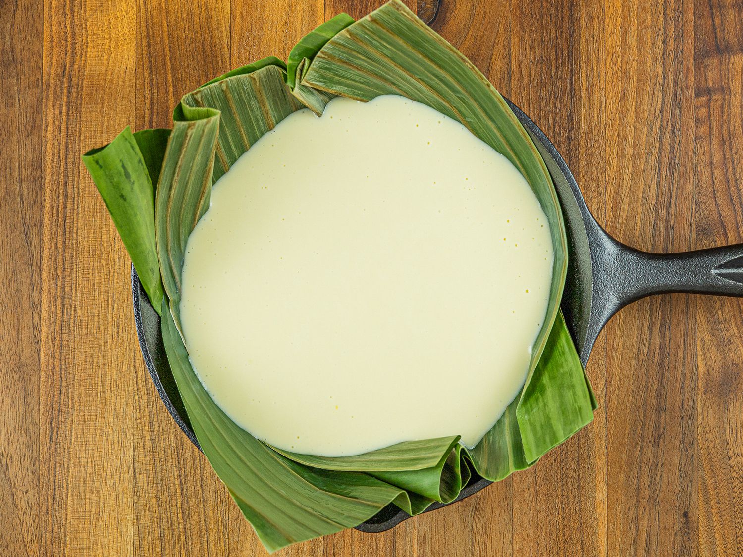 Bibingka batter in banana leaf-lined cast iron pan