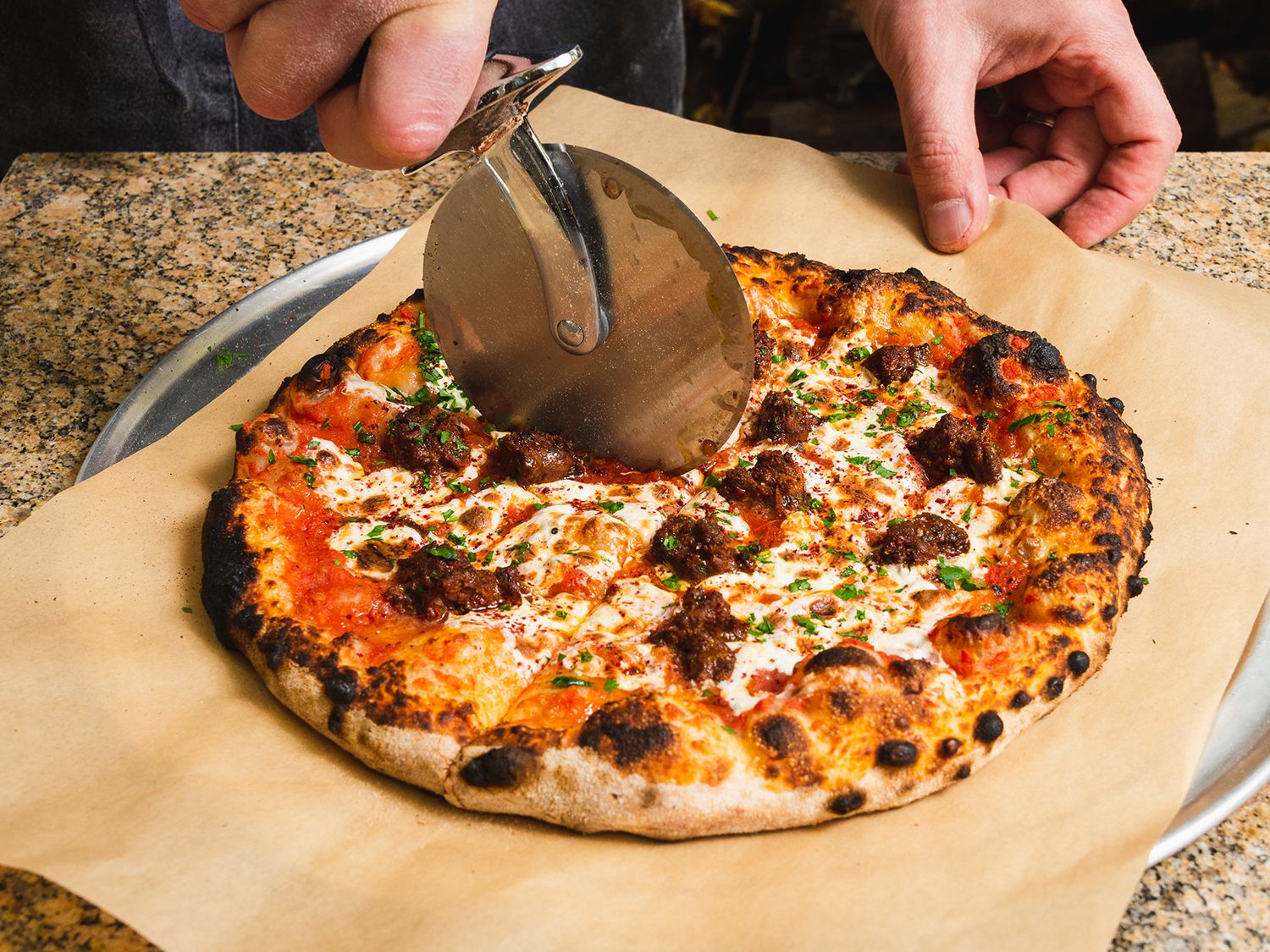 Sliding a charred broccoli rabe pizza onto a serving tray