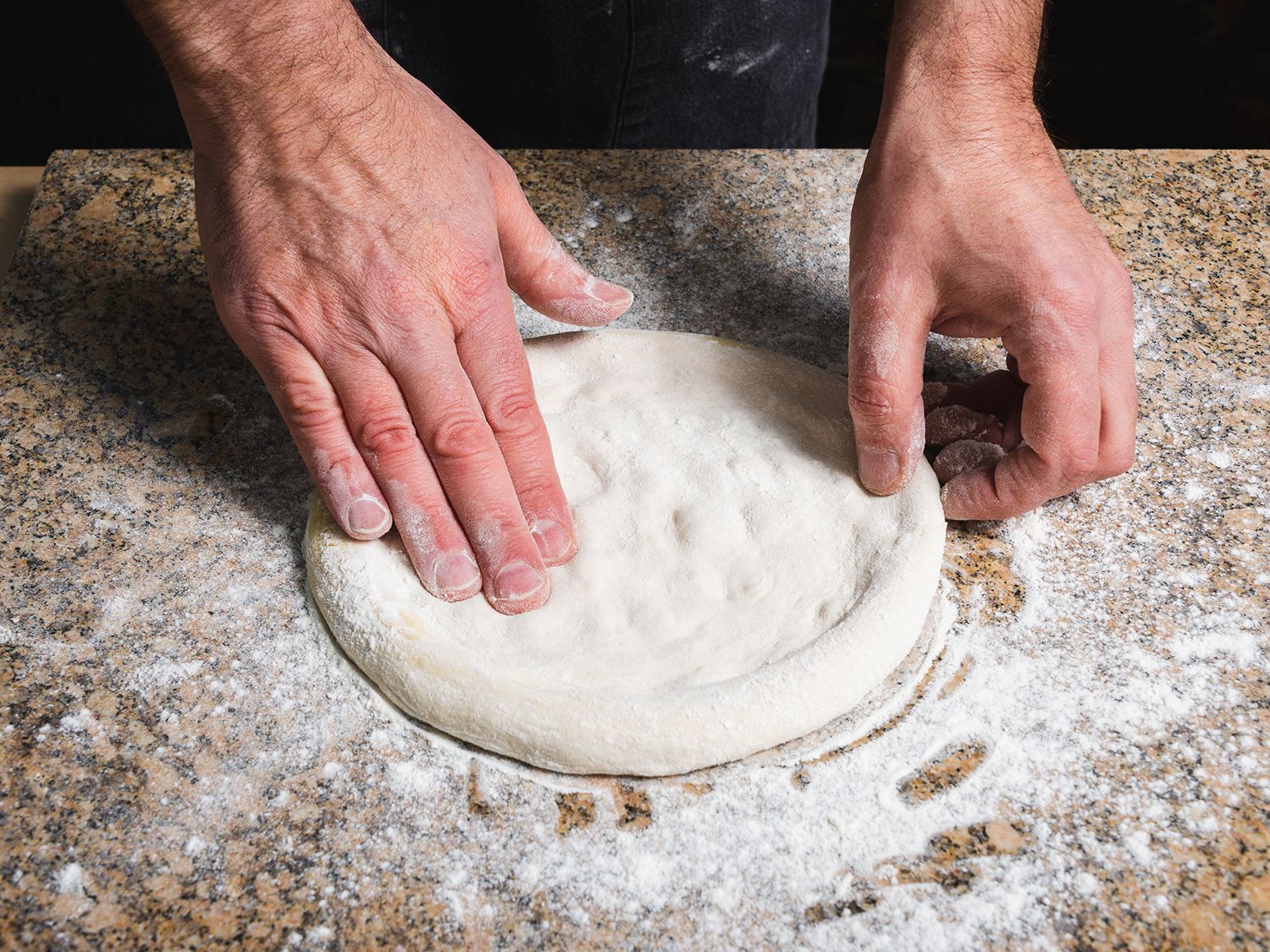 Topping stretched pizza dough with tomato sauce, anchovies, grated cheese, charred rabe, and olive oil.