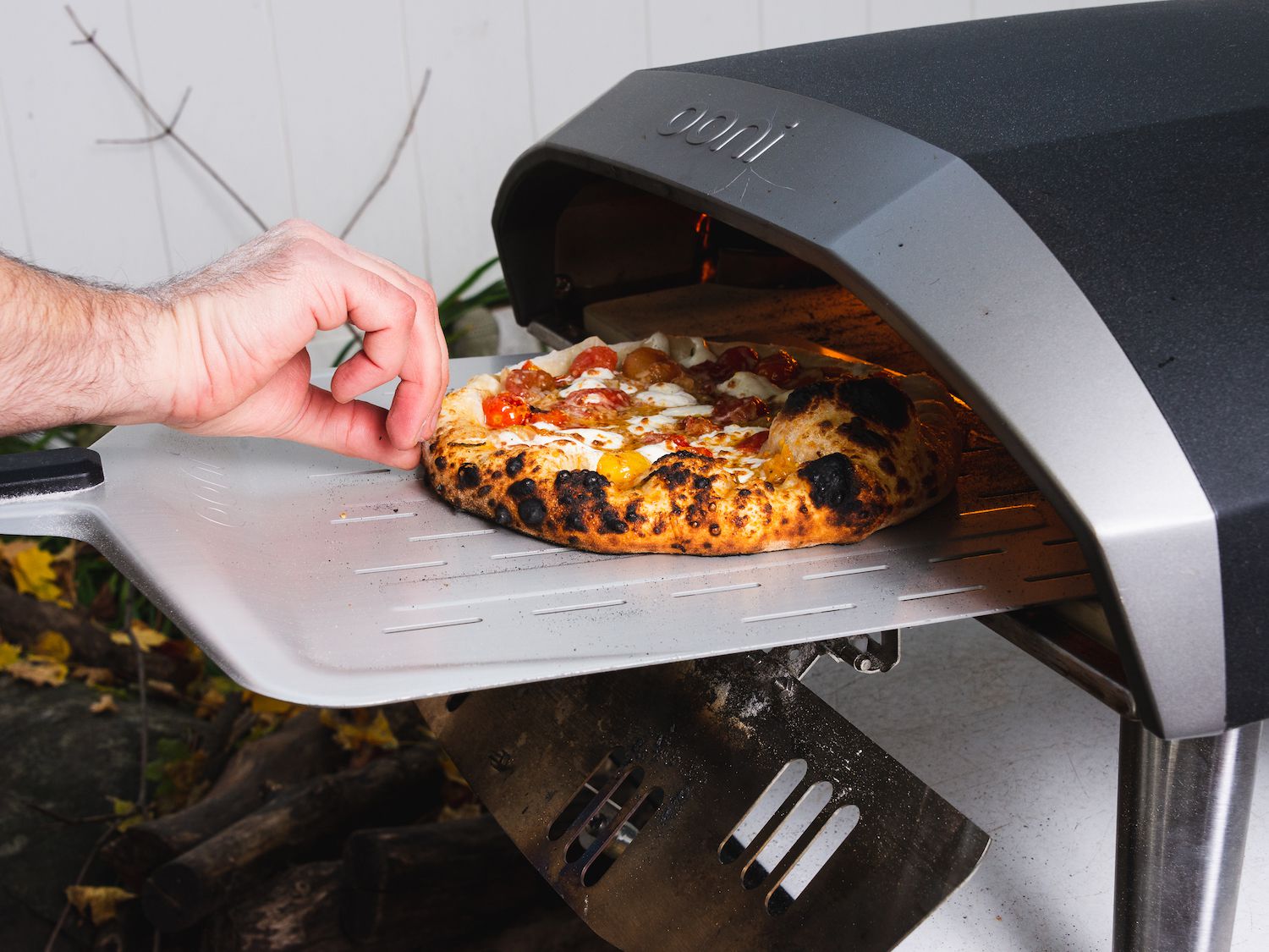Hands shaping outdoor pizza oven pizza dough on a floured counter