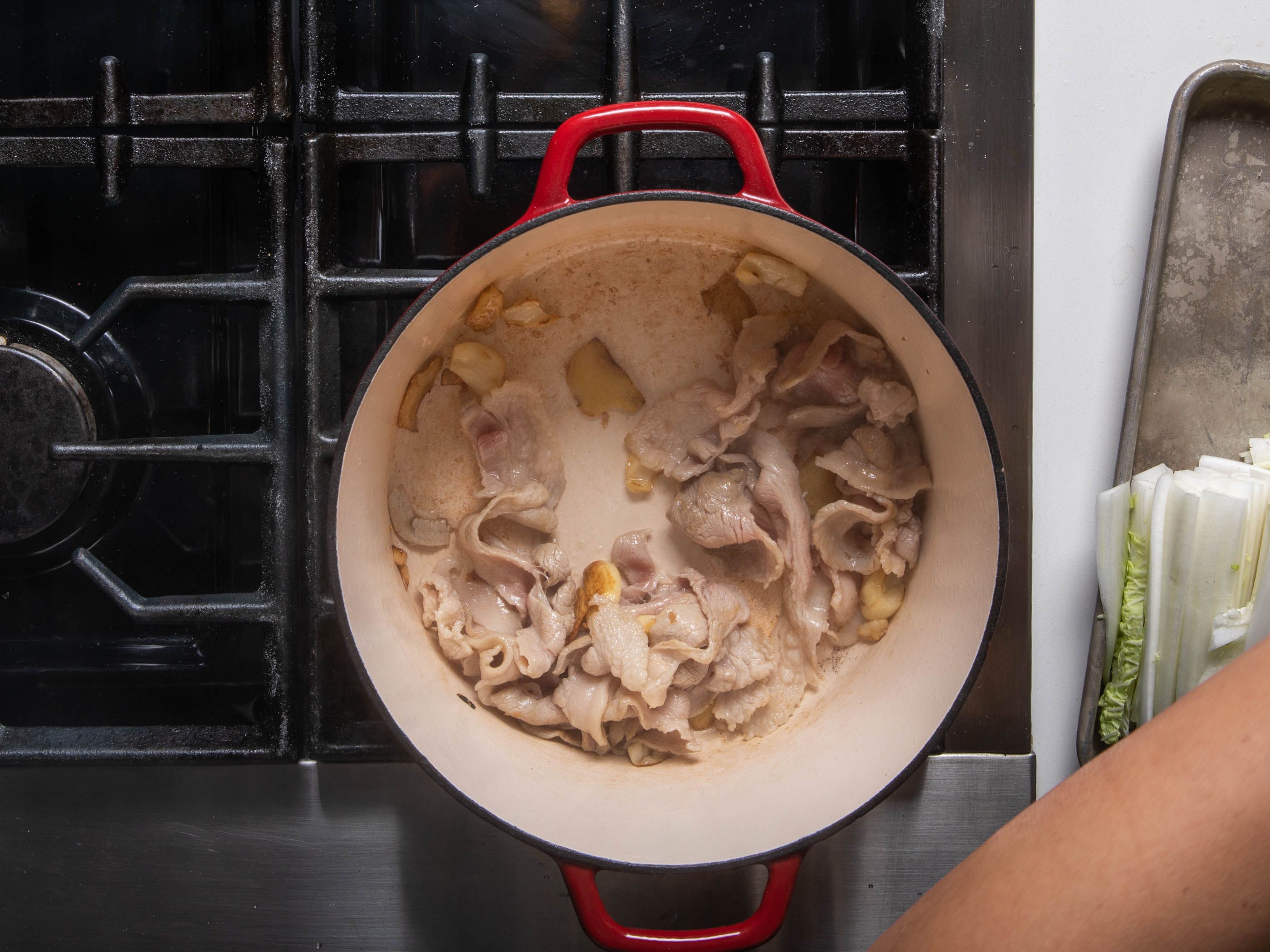 Pork and aromatics sauteeing in a dutch oven