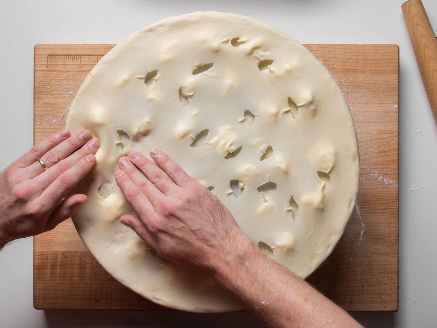 Tearing holes in the top layer of dough for focaccia di Recco