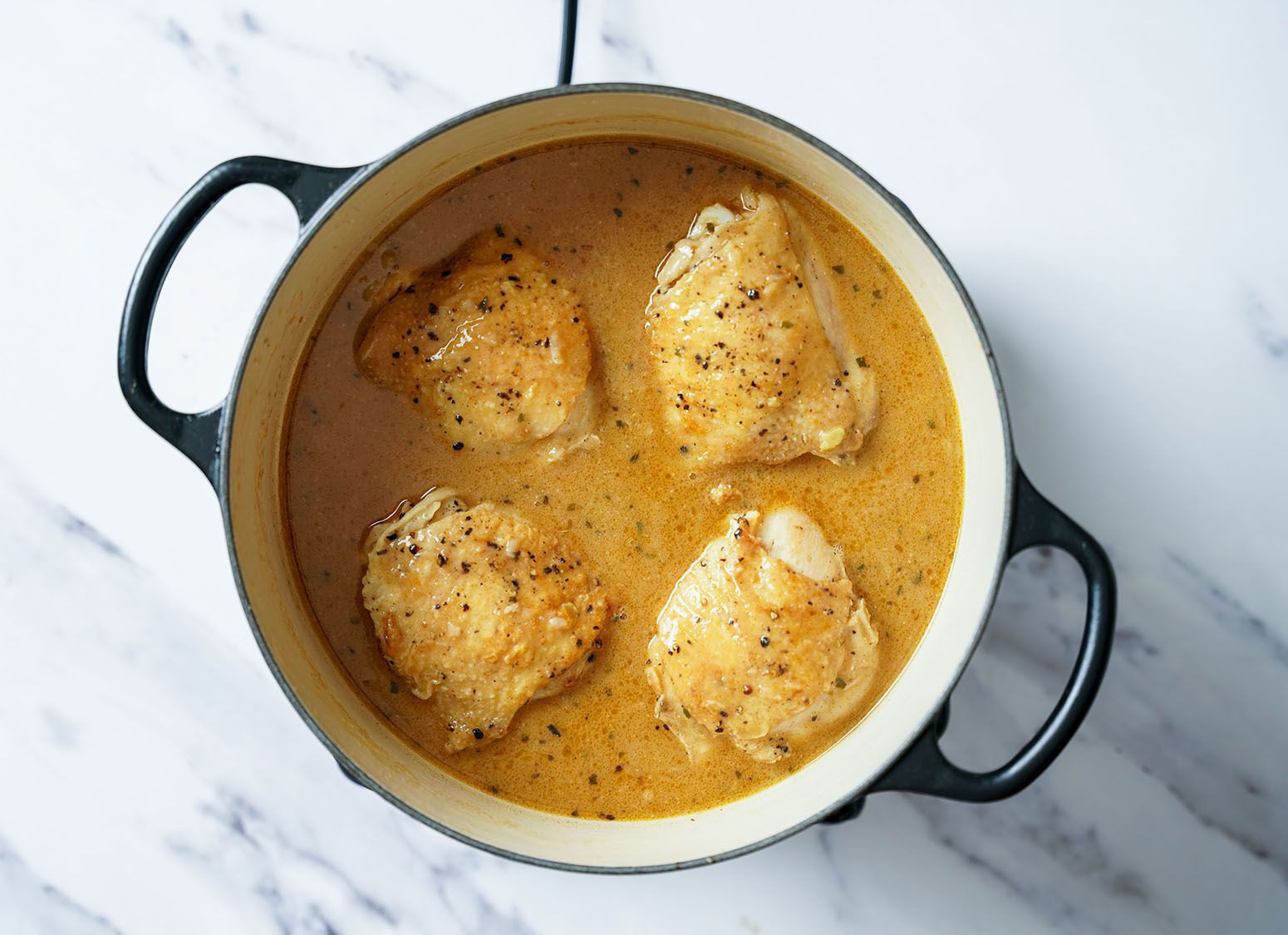 Chicken simmering in sauce.