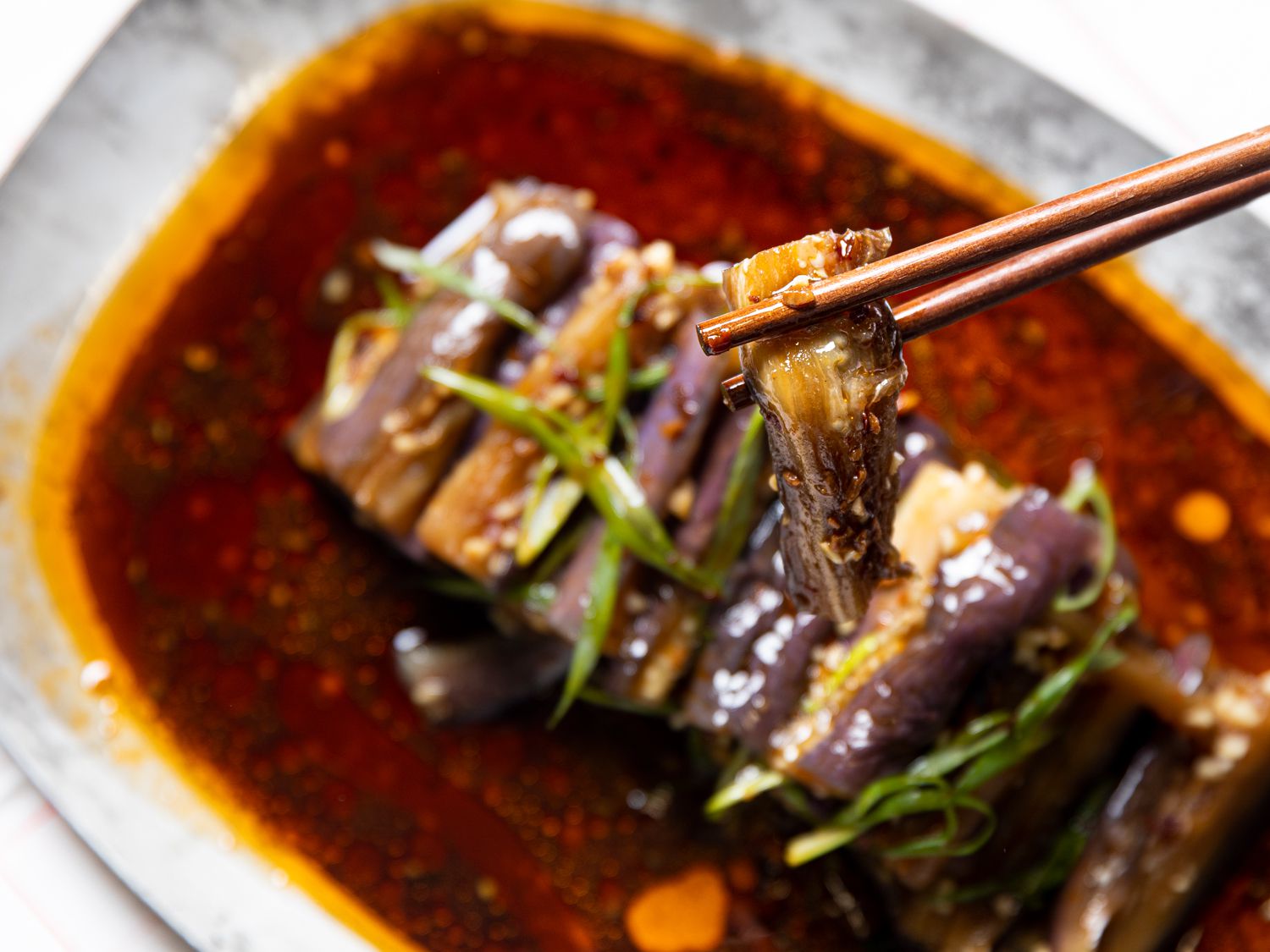 Chopsticks holding up a piece of eggplant