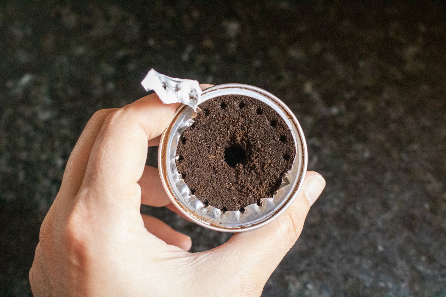 An overhead shot at a spent Nespresso capsule with the foil top removed so you can see the grounds