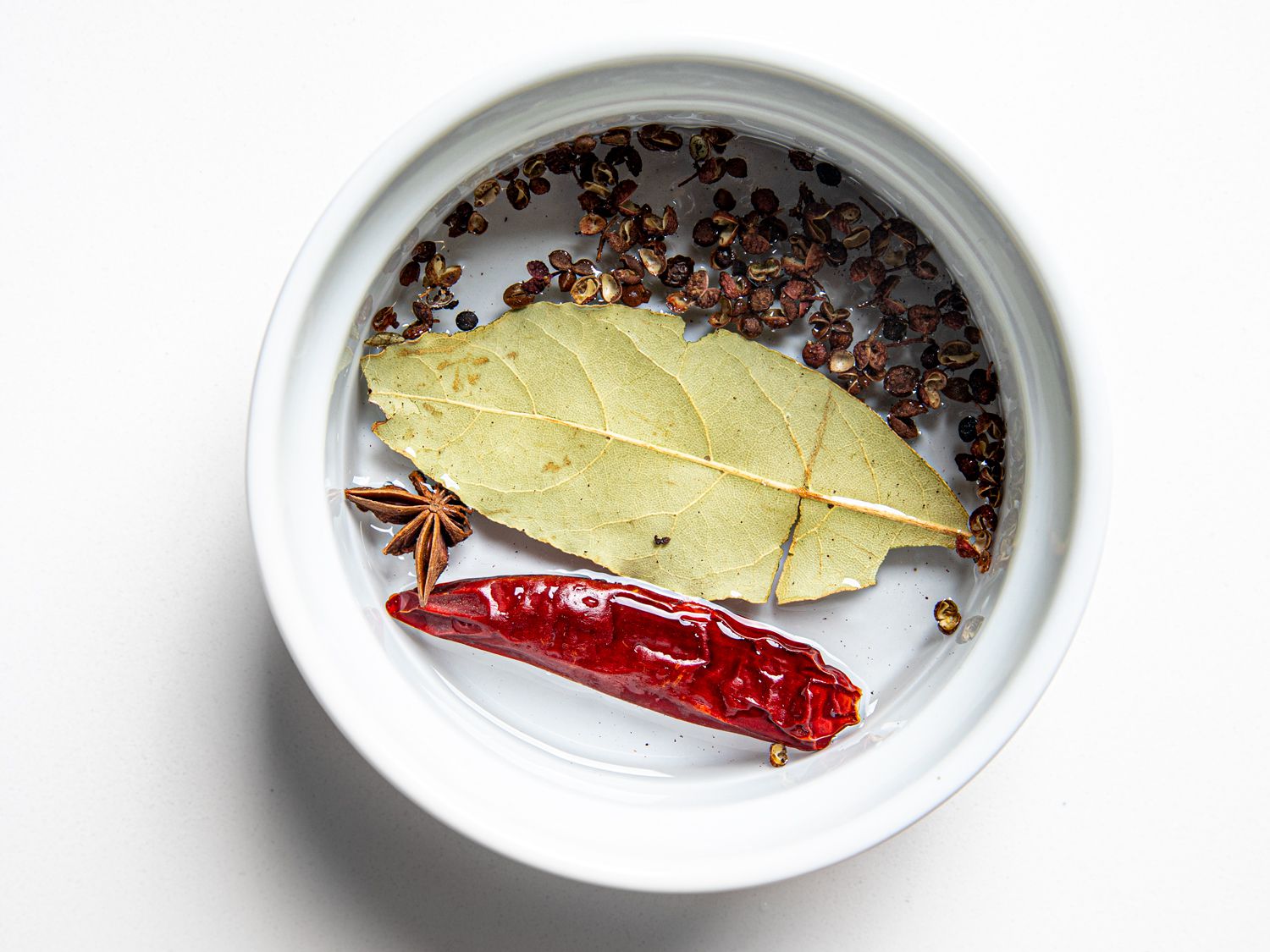 Bay left, pepper, and anise in a small round bowl