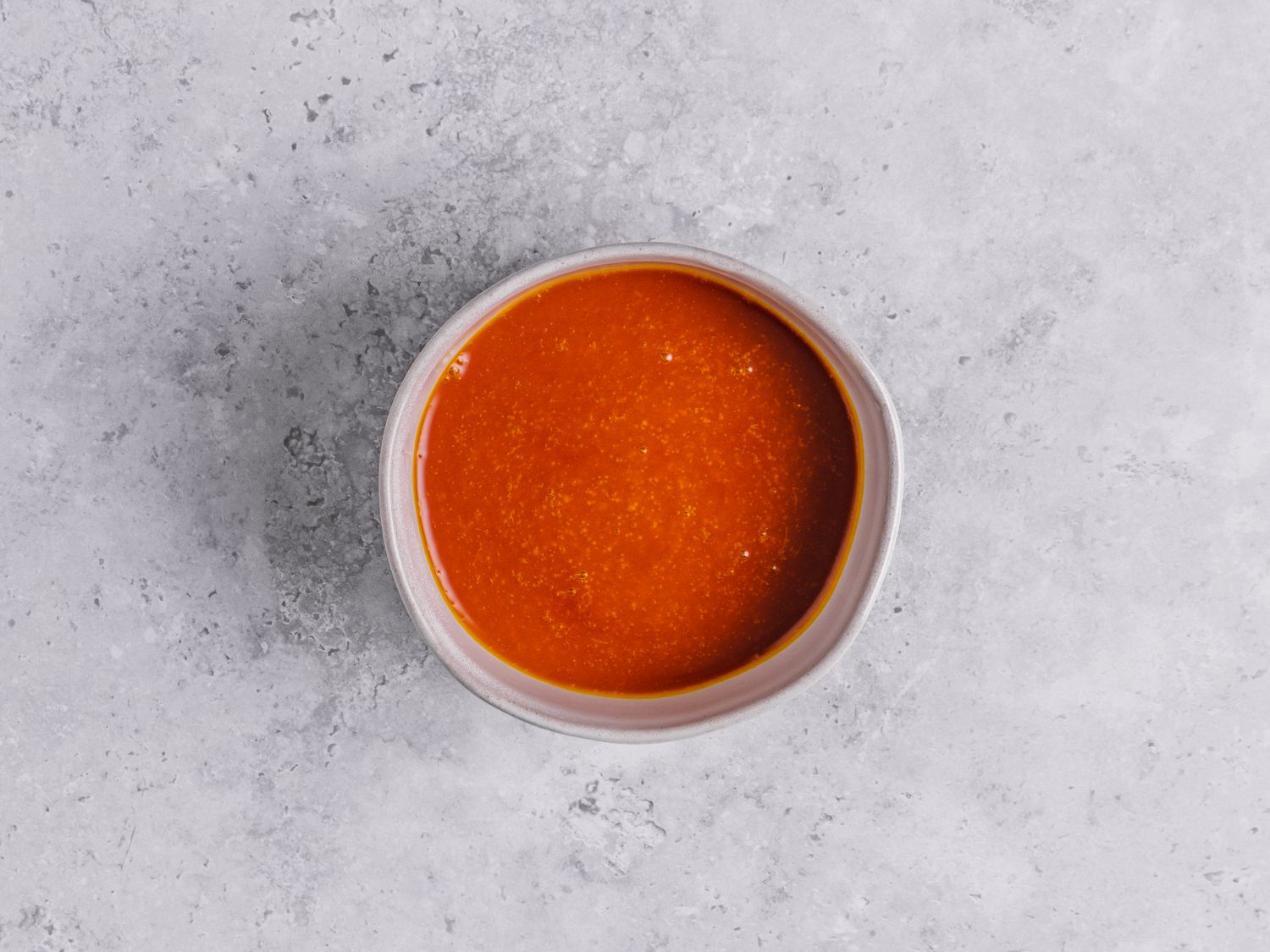 Palm oil in a bowl on a marbled grey surface
