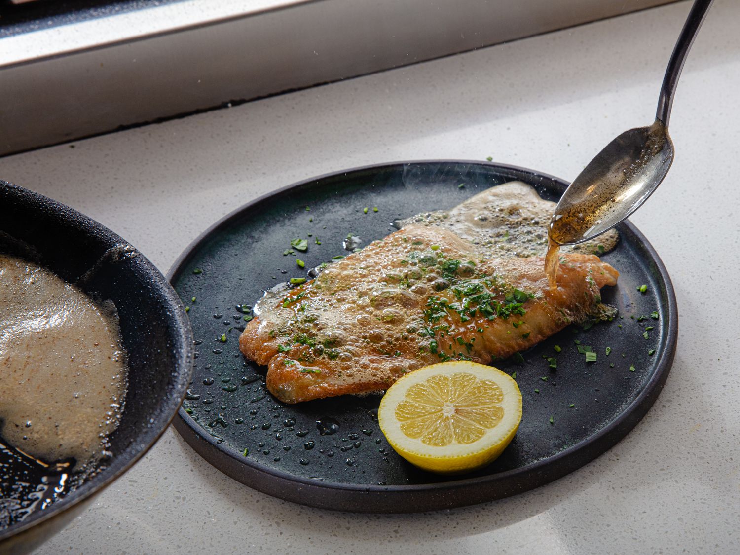 Hot brown butter being spooned straight from the pan over the fish