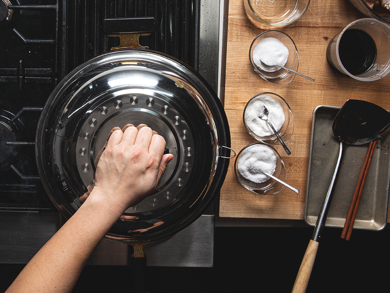 A hand placing a life on a wok next to a wok station