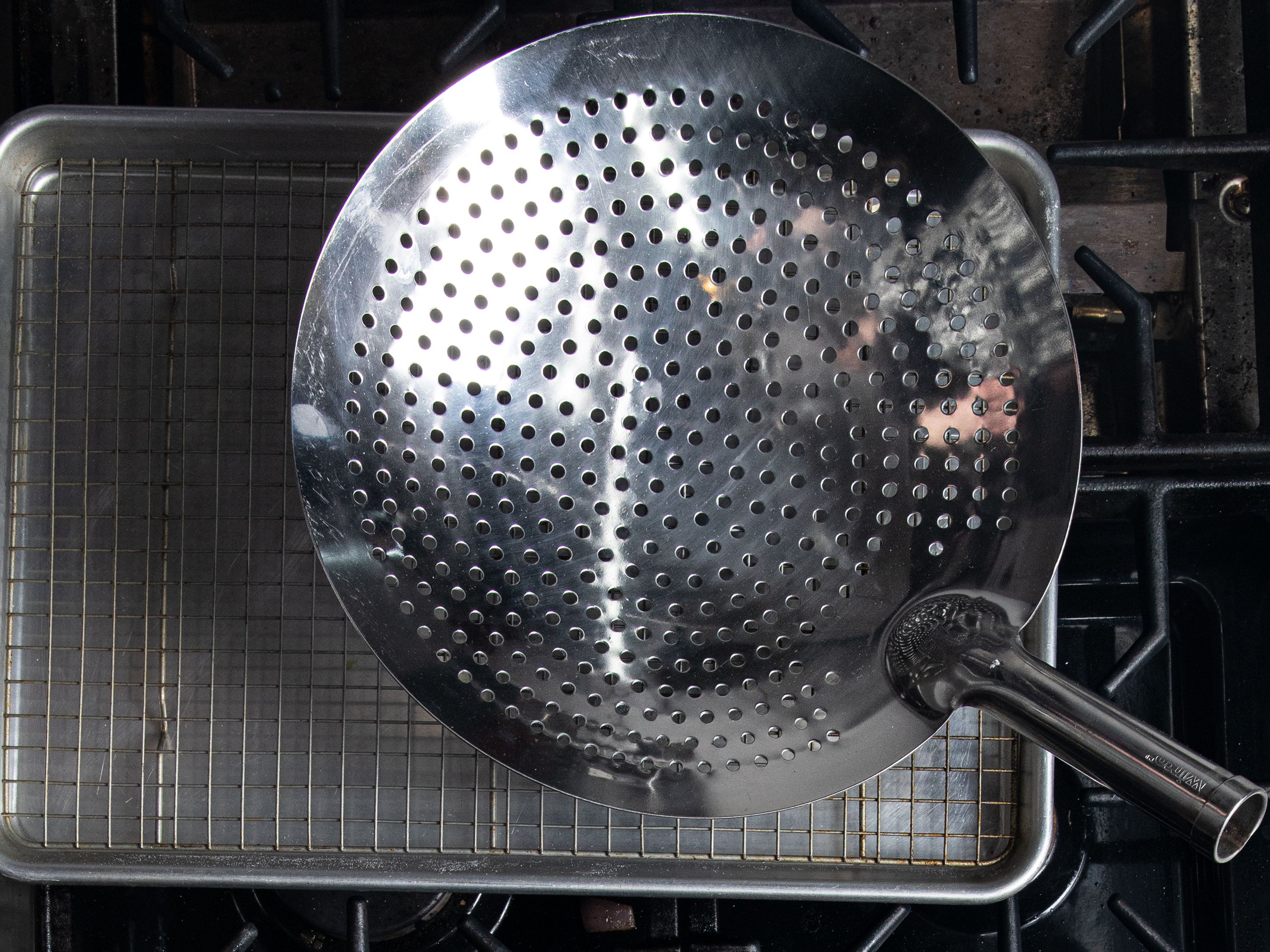 A perforate skimmer resting on top a stove
