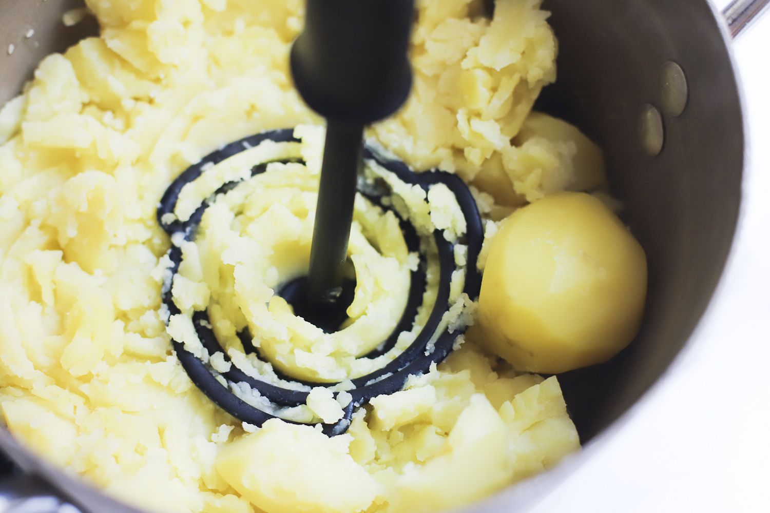 The Dreamfarm potato masher mashing potatoes in a saucepan