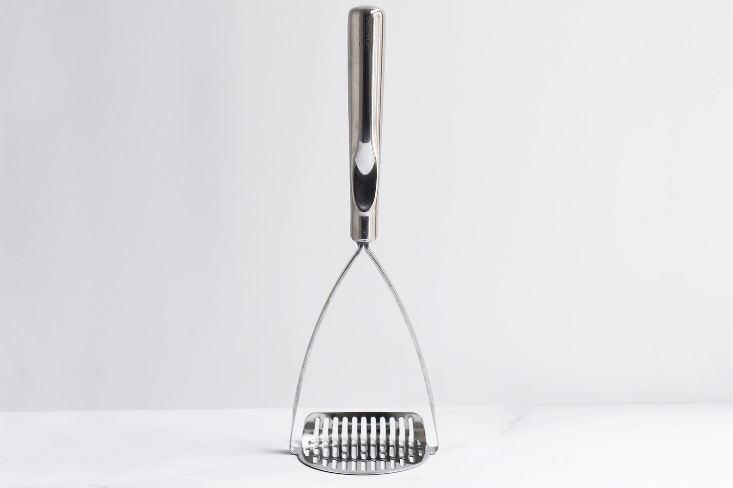 All-Clad potato masher against a white background