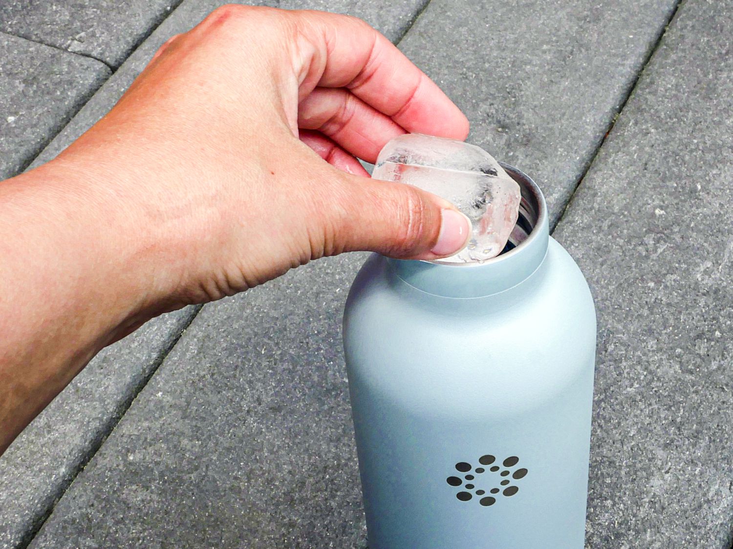 A hang adding ice to a stainless steel water bottle