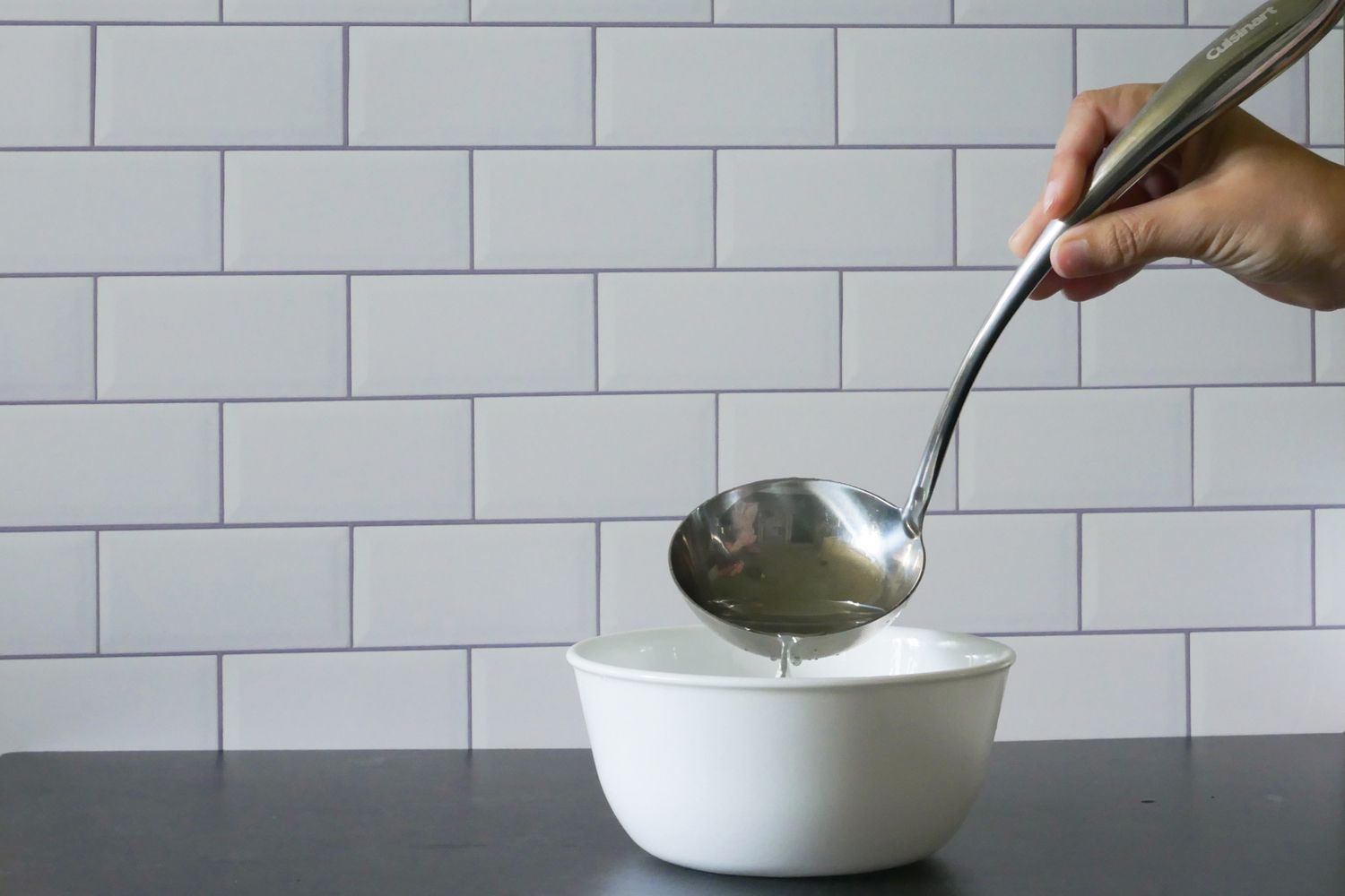 using the cuisinart ladle to empty water into a bowl to demonstrate the bowl shape.