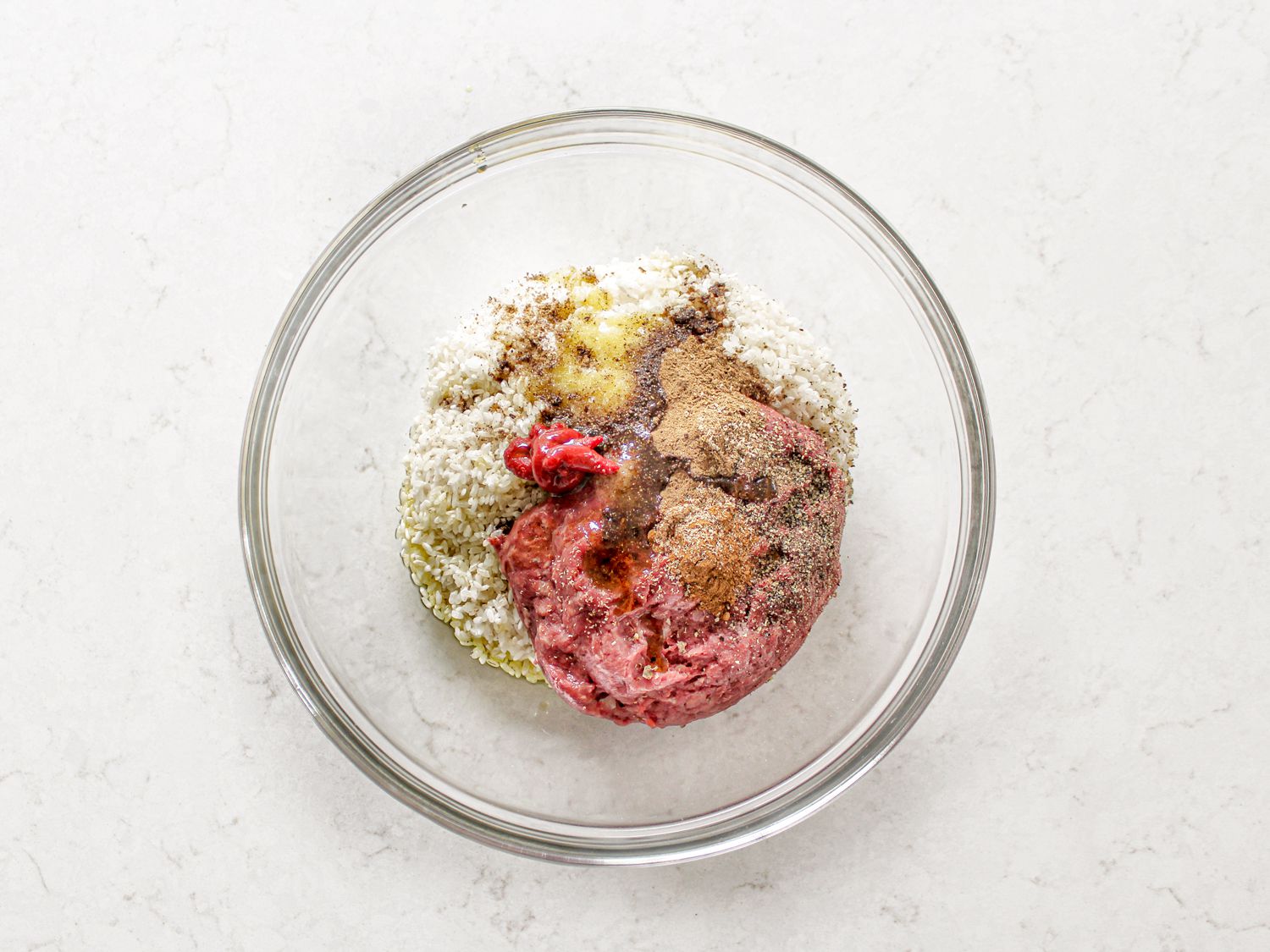 Ingredients for meat mixture inside grape leaves in a glass bowl