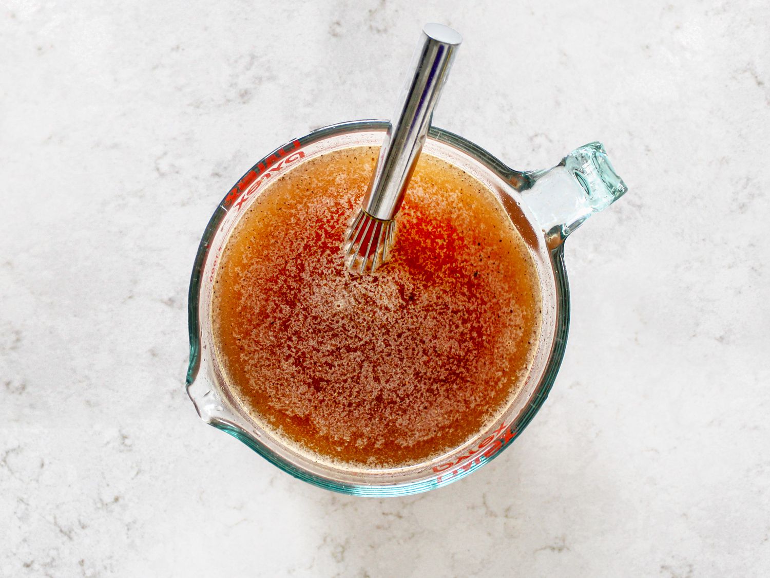 Broth mixture in a measuring cup with whisk
