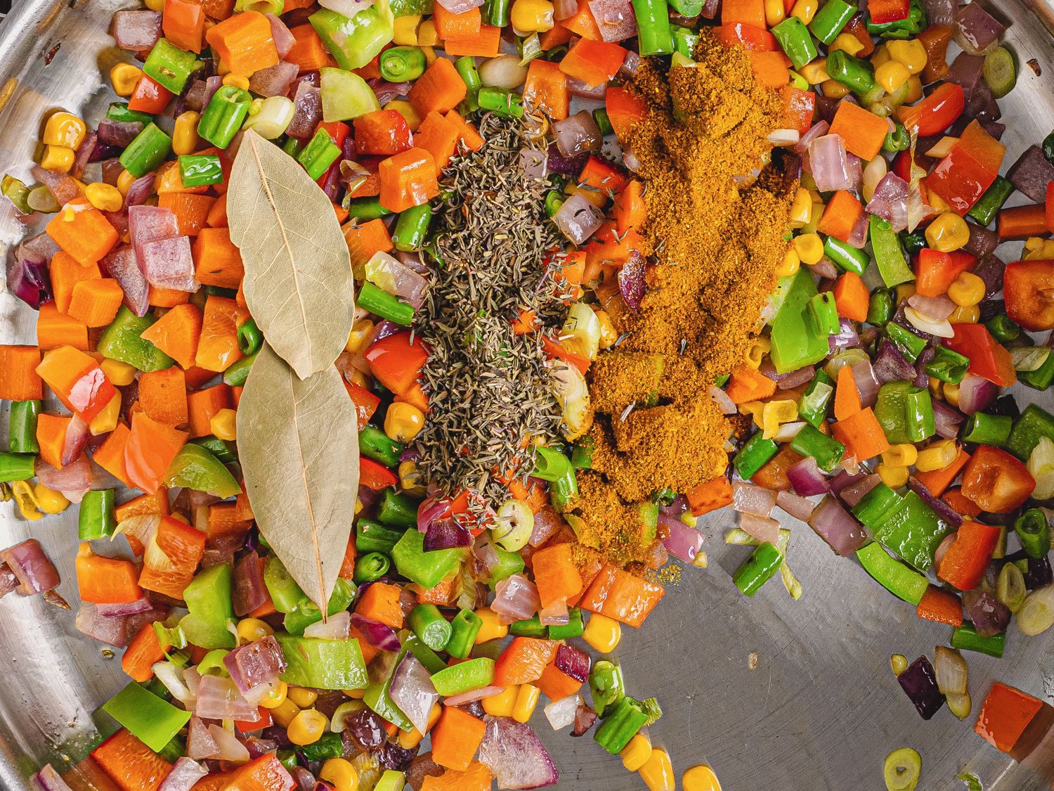 Seasonings added to softened vegetables in pan