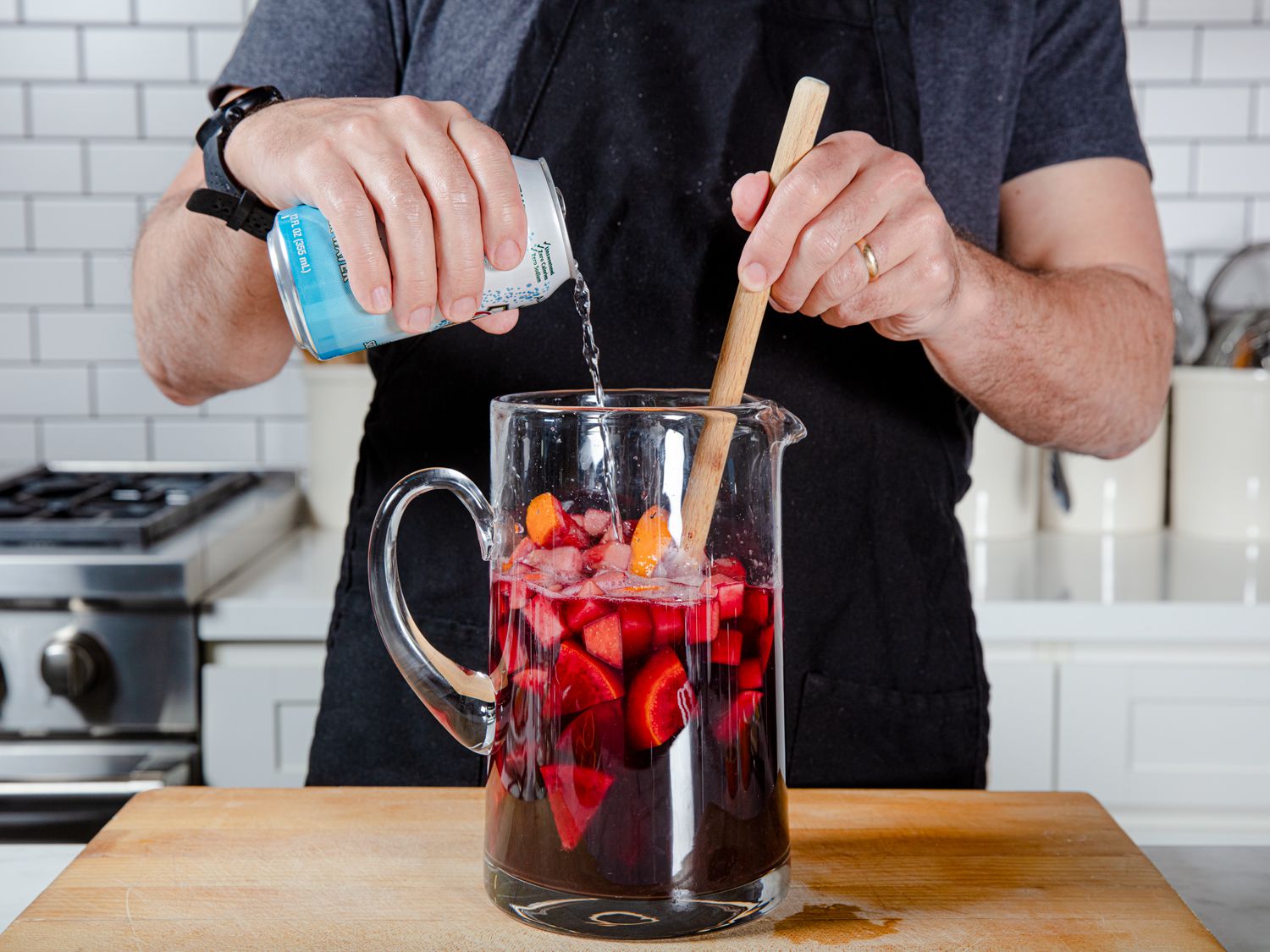 Chef stirring club soda into a pitcher of sangria.