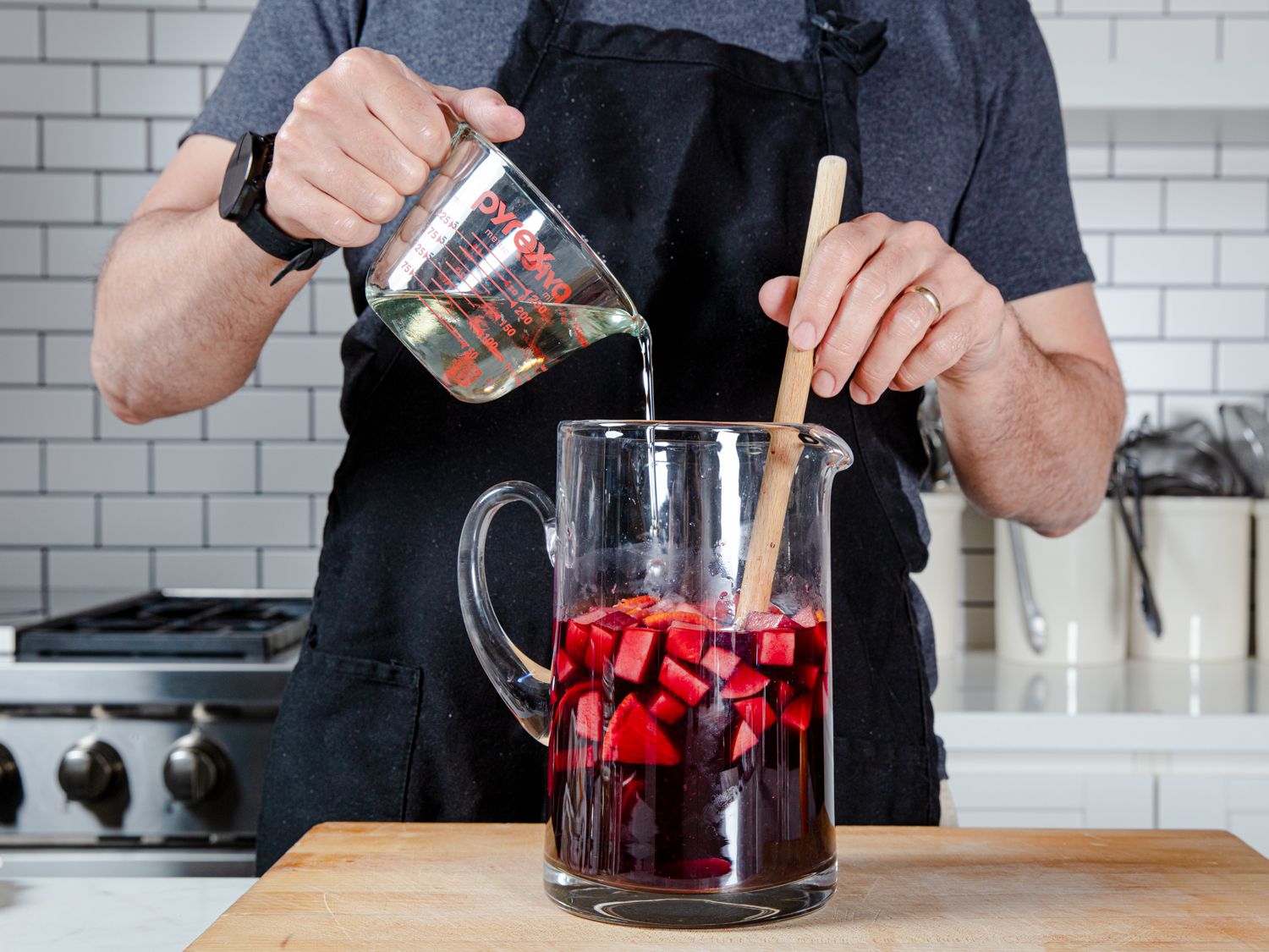 Chef stirring simple syrup into a pitcher of sangria.
