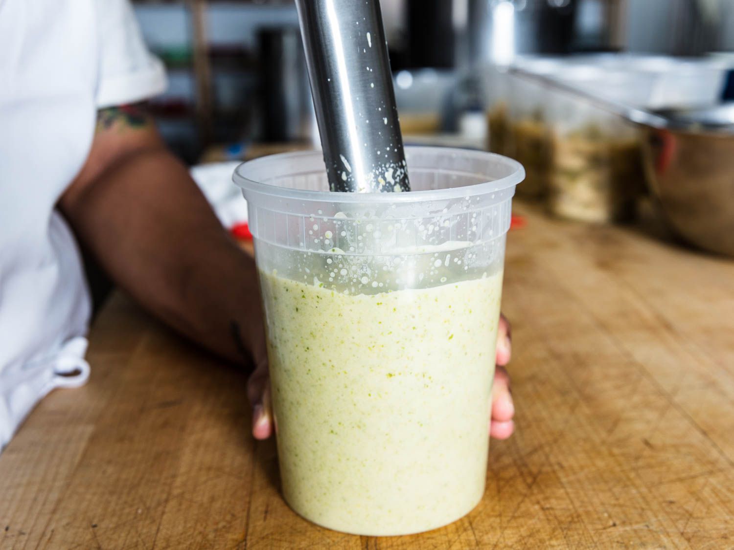 Puréeing celery soup in a plastic container using an immersion blender