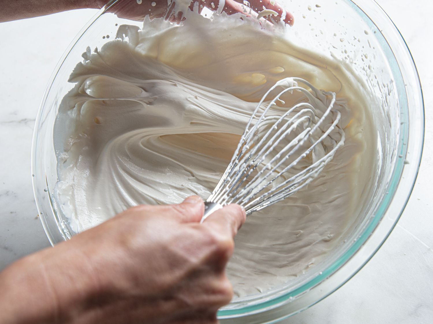 A hand making whipped cream with a whisk