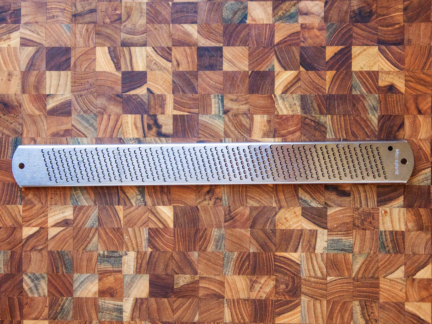 a stainless steel microplane on a wooden surface