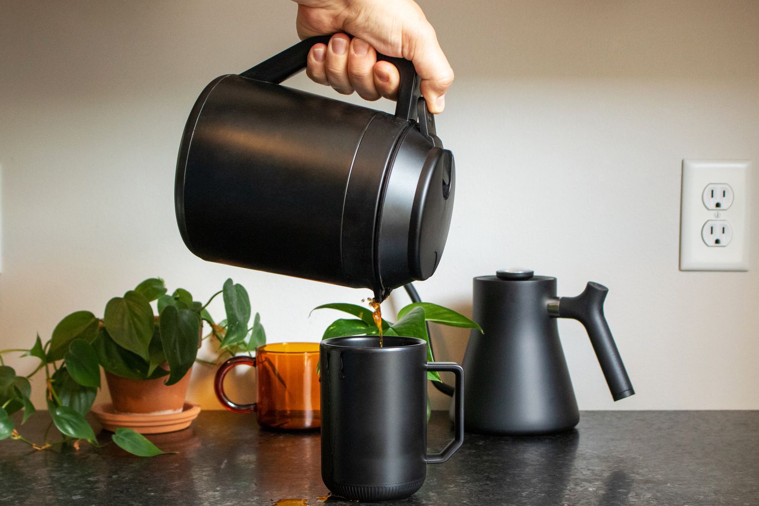 A thermal carafe pouring coffee into a temperature control mug
