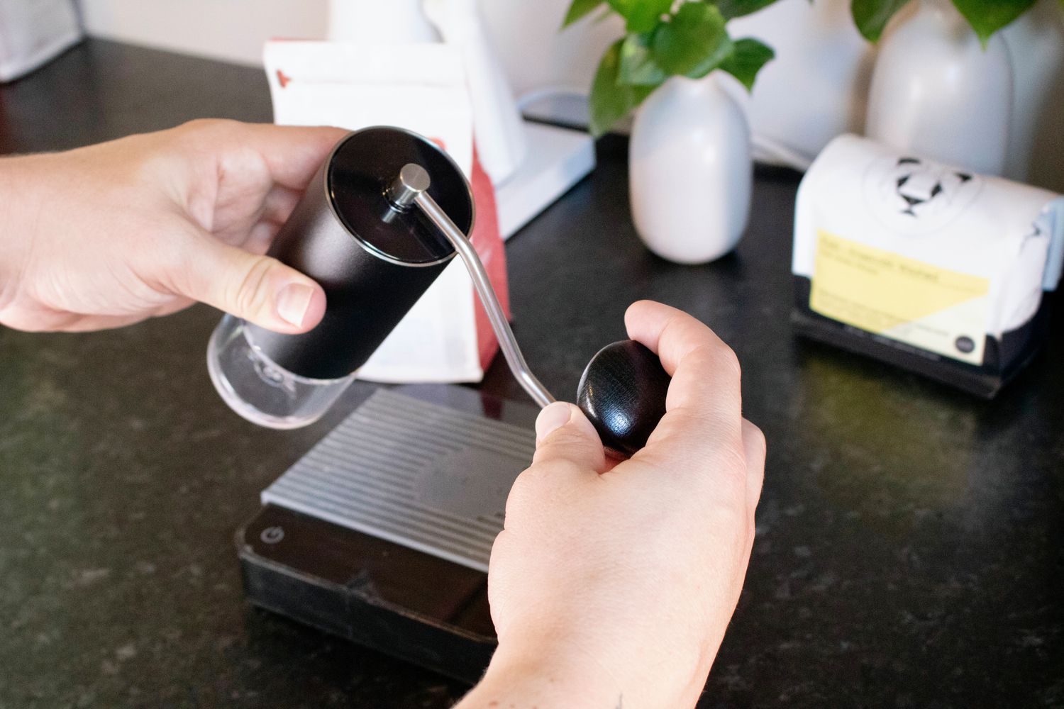 a handheld grinder is being held and cranked by hand