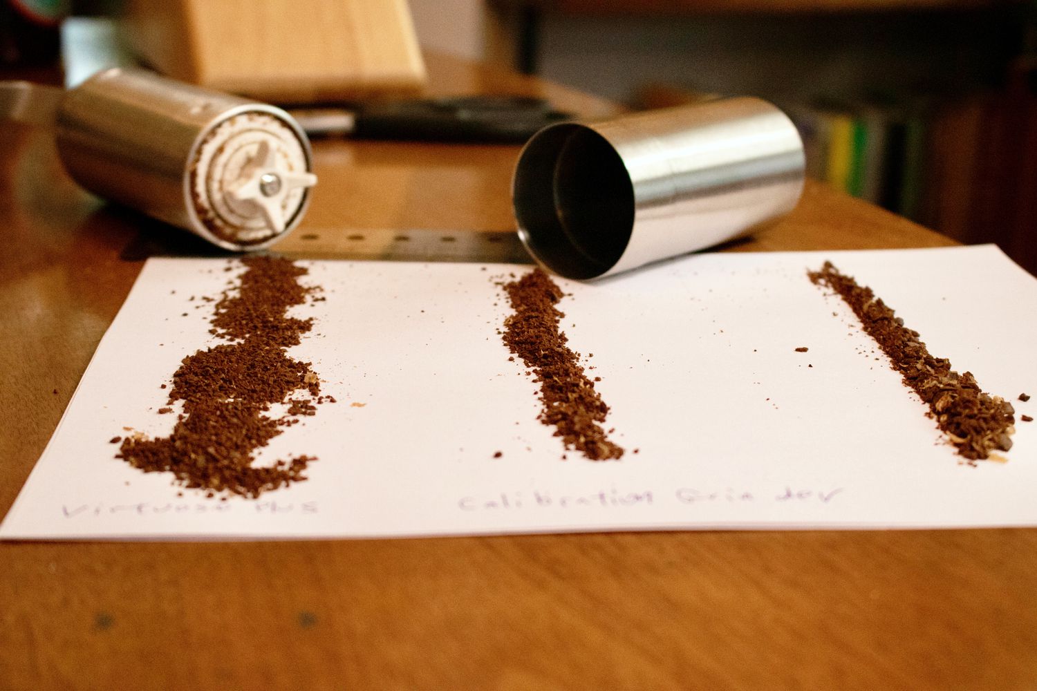 a white piece of paper has coffee grounds lined up on it side by side to compare sizes