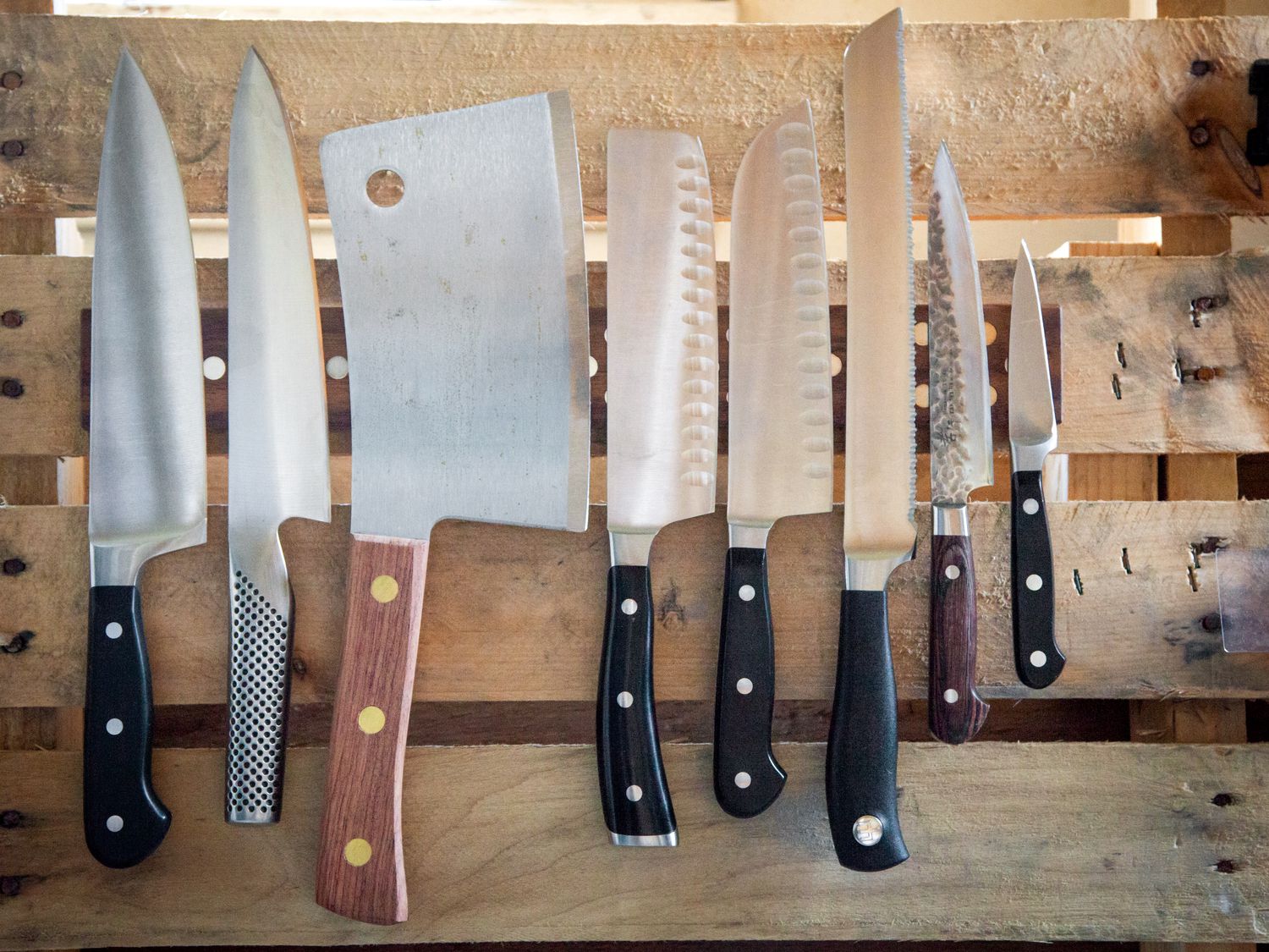 a magnetic knife bar with several knives on it affixed to a wooden pallet