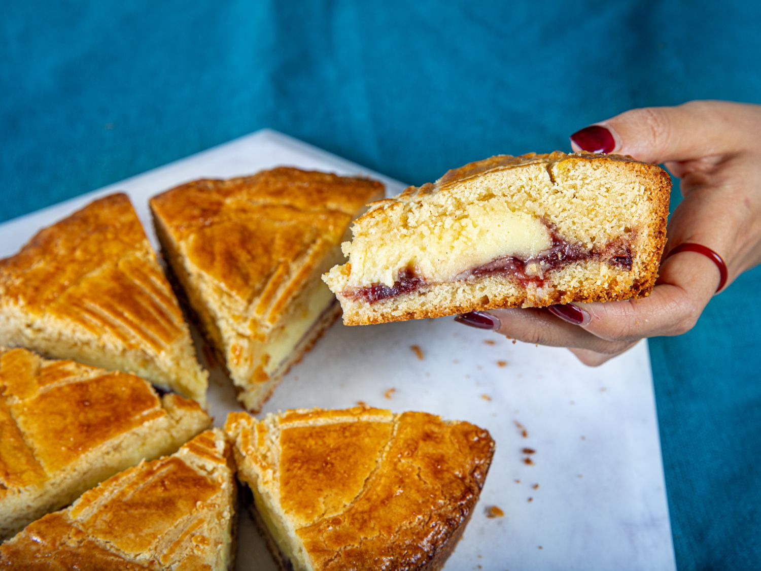 A hand holding up a piece of gateau basque