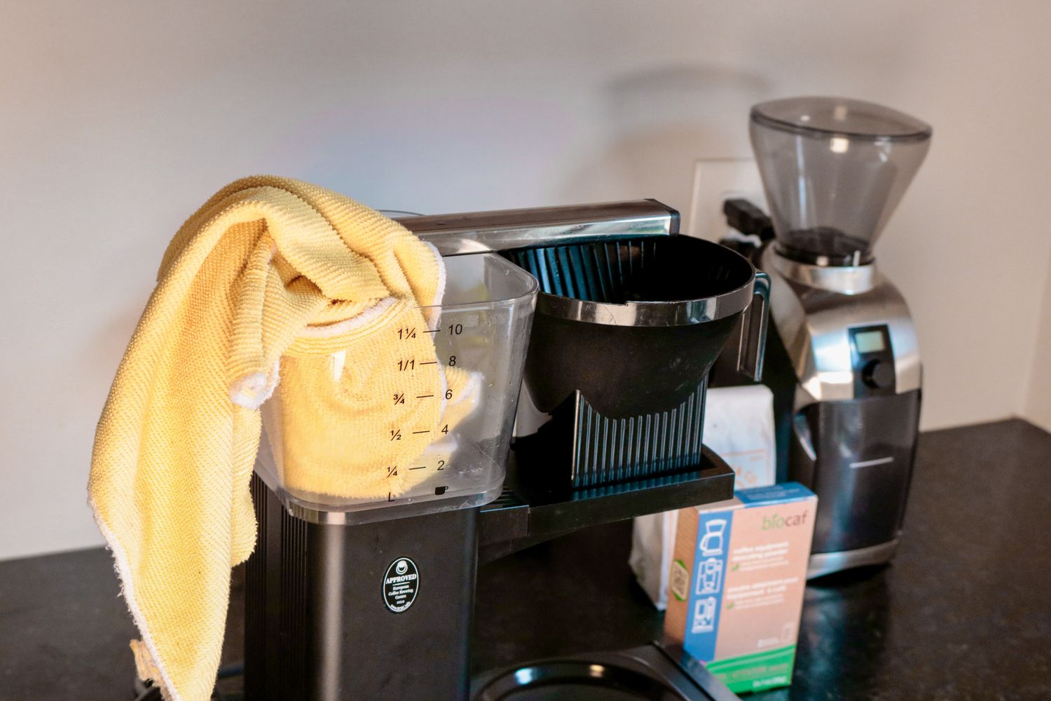 a yellow microfiber cloth sticking out of the water reservoir of a coffee maker