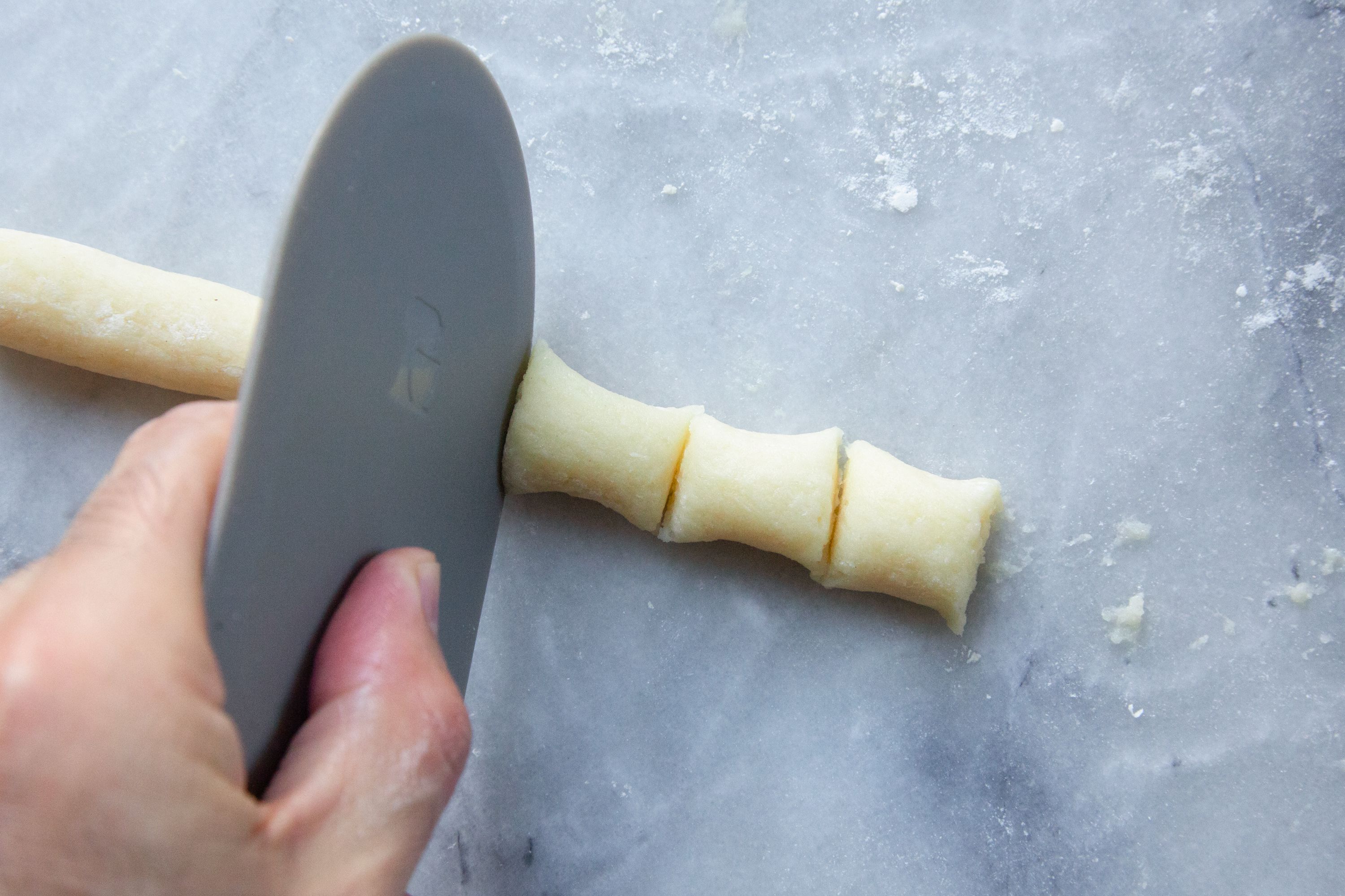 using a bowl scraper to cut gnocchi