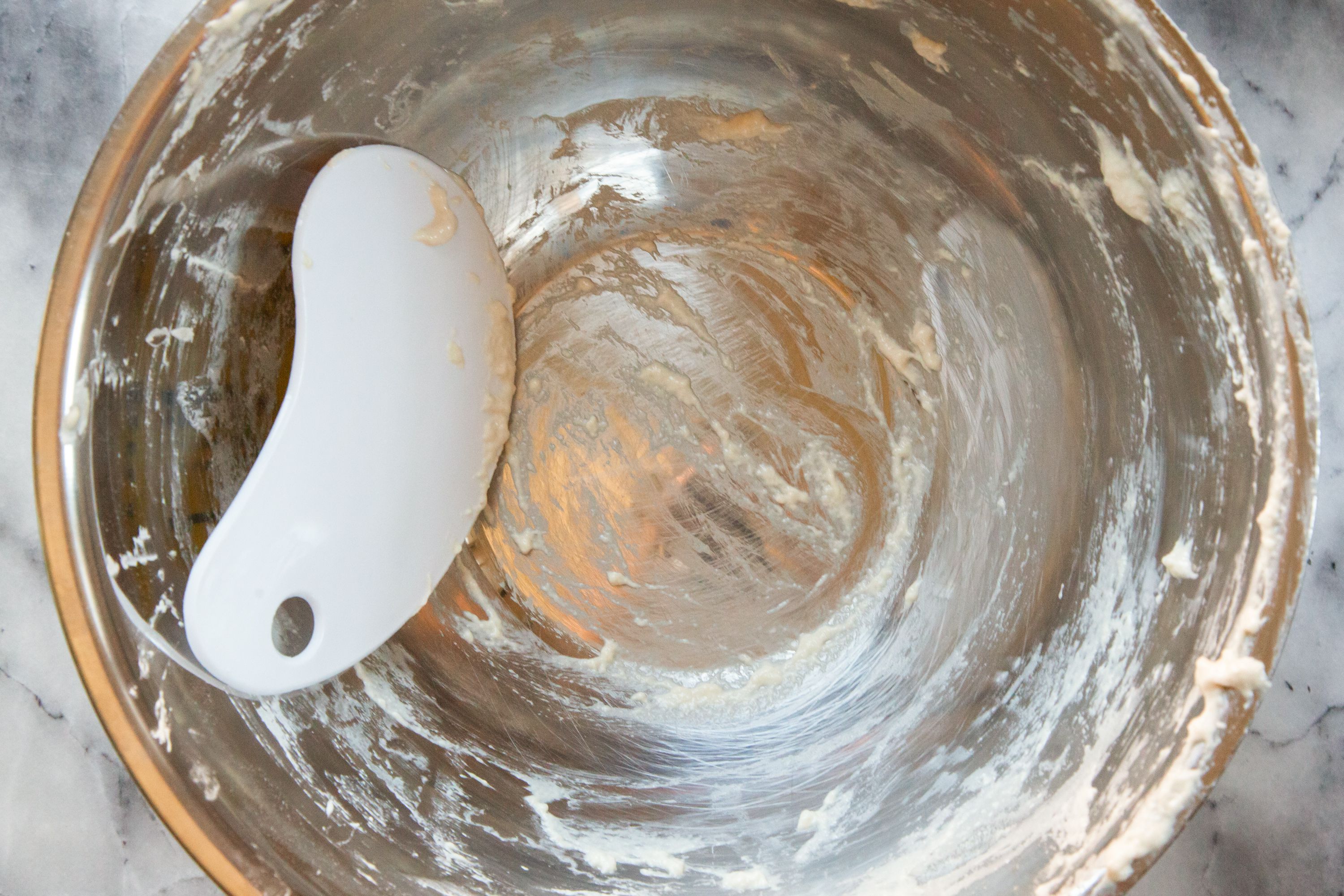 bowl scraper in a bowl with dough scraped around the bowl interior.