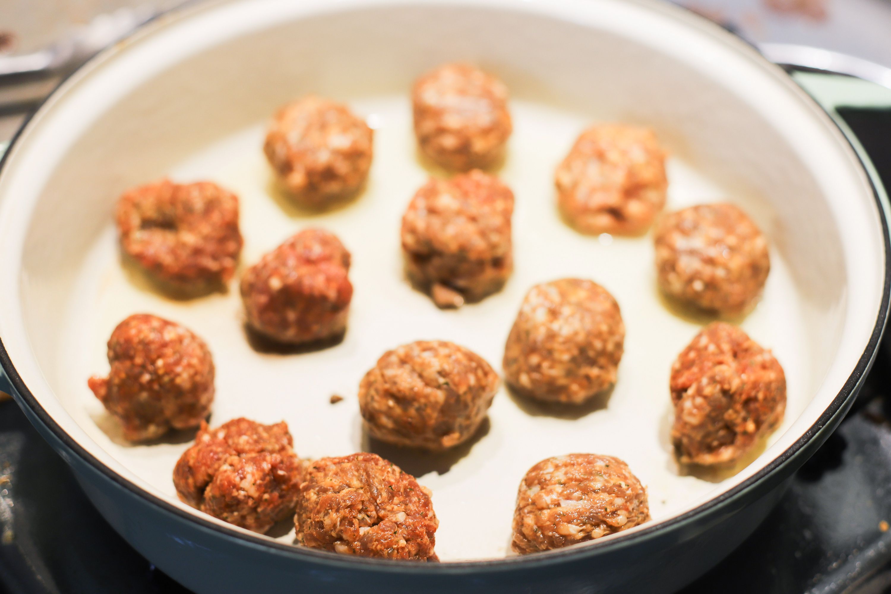An enameled cast iron braiser with meatballs in it