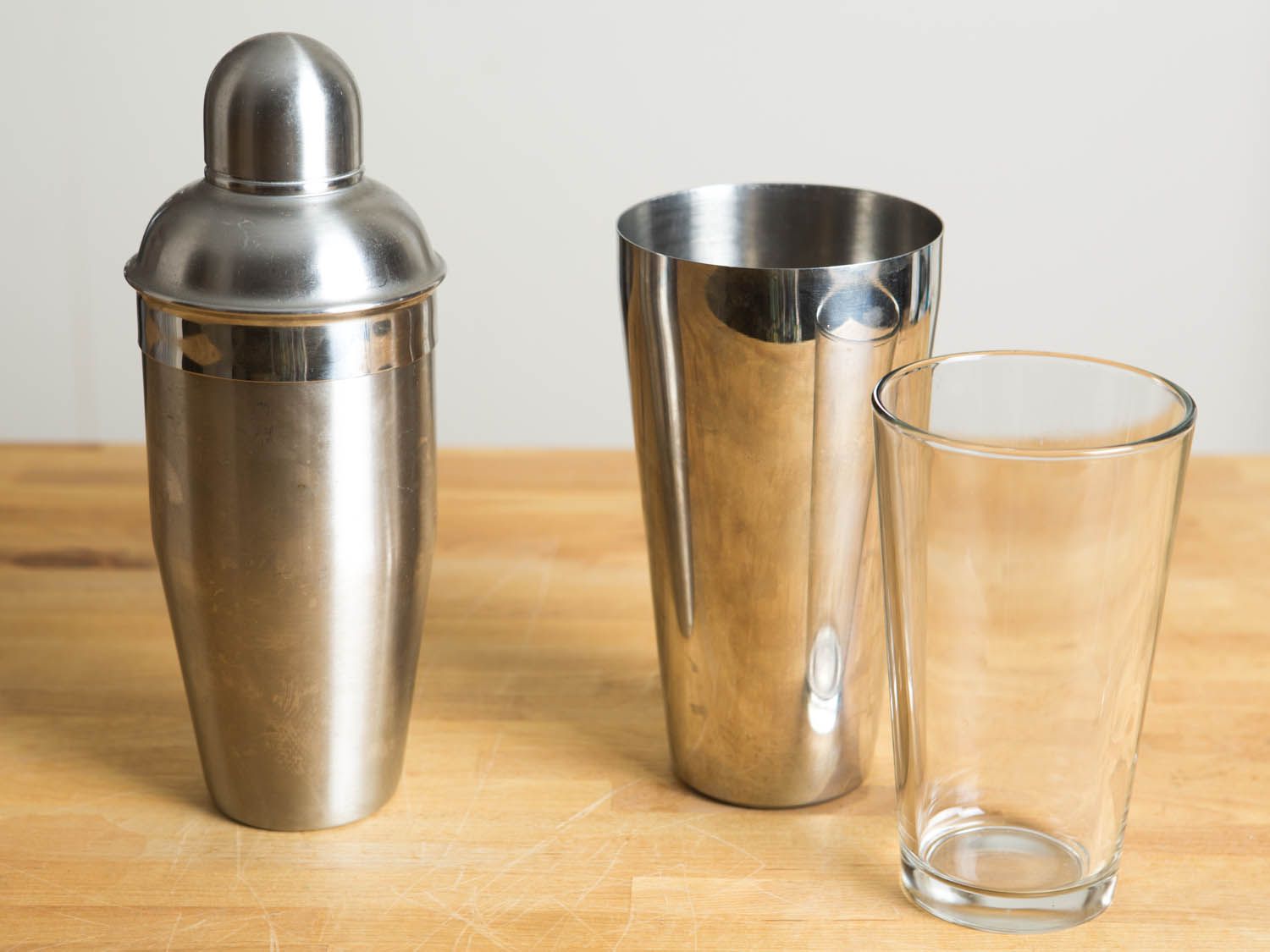 a cobbler and a boston shaker side by side on a wooden countertop