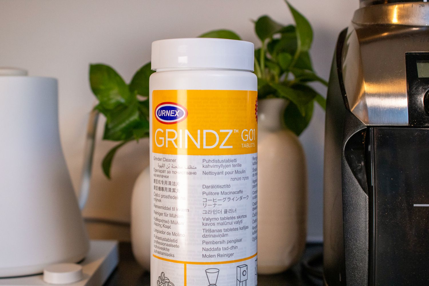 A bottle of Grindz on a coutertop next to a gooseneck kettle and a burr grinder