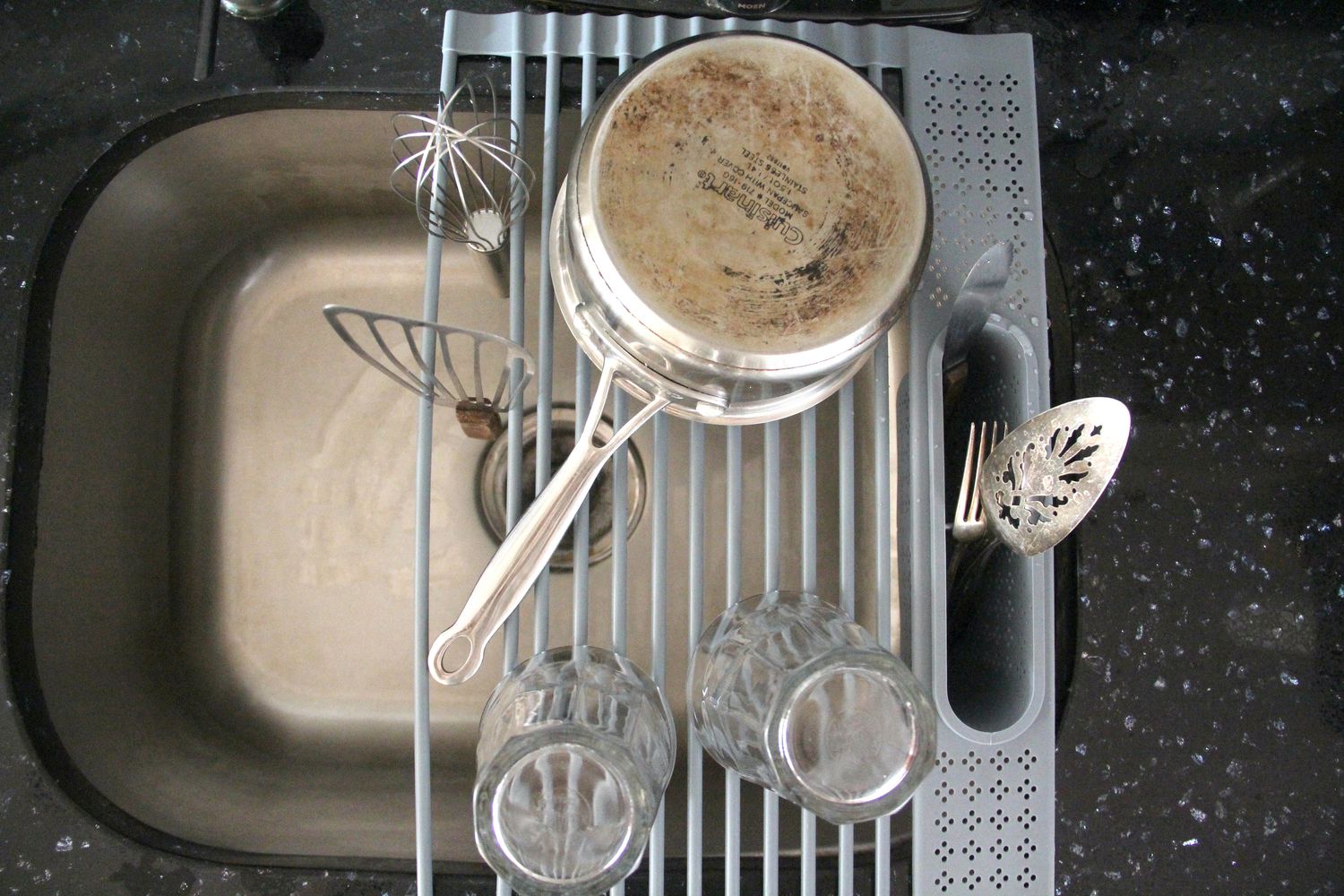 a pot, glasses, whisk, fish spatula, and utensils on the food52 dishrack over the sink.