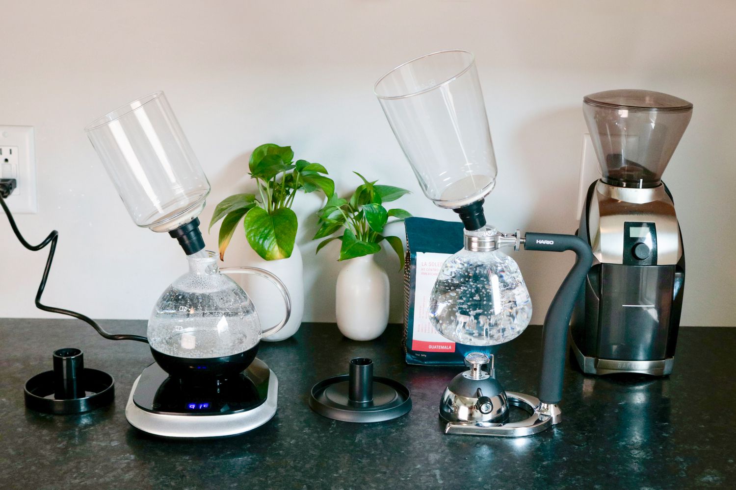 two siphon brewers on a grey countertopâÂÂone with boiling water and one with brewed coffee in the bottom