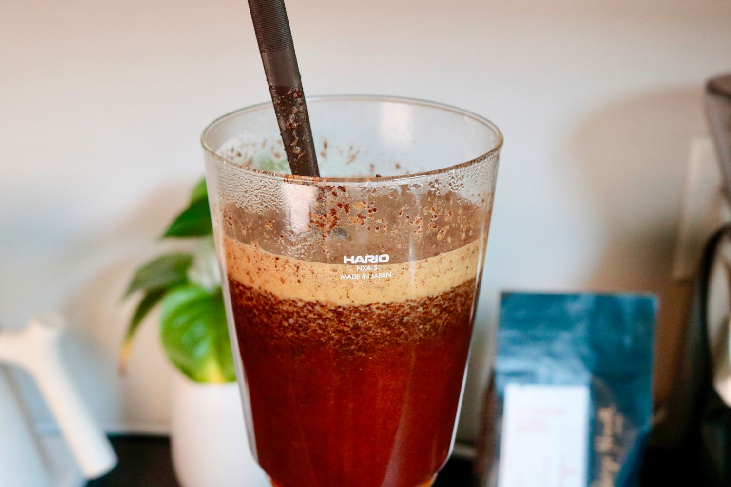 a closeup look at grounds in the top canister of a siphon brewer being stirred with a spoon